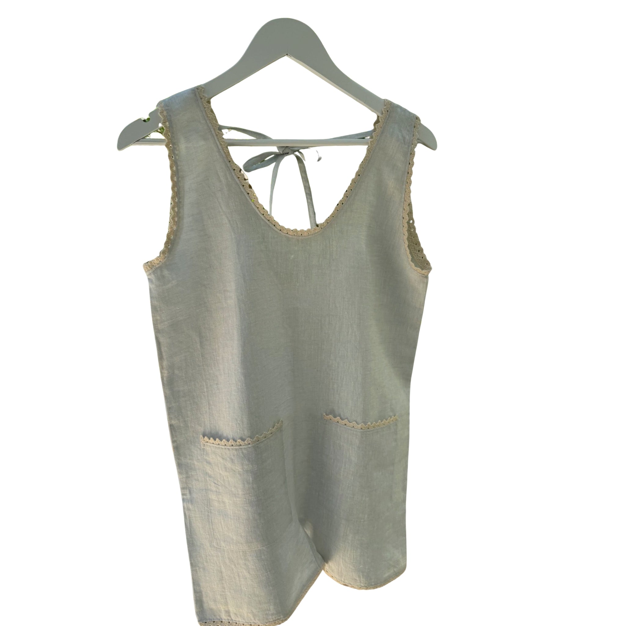 Front of a light blue women's playsuit hanging on a white hanger with patch pockets and ric rac details and tie back.