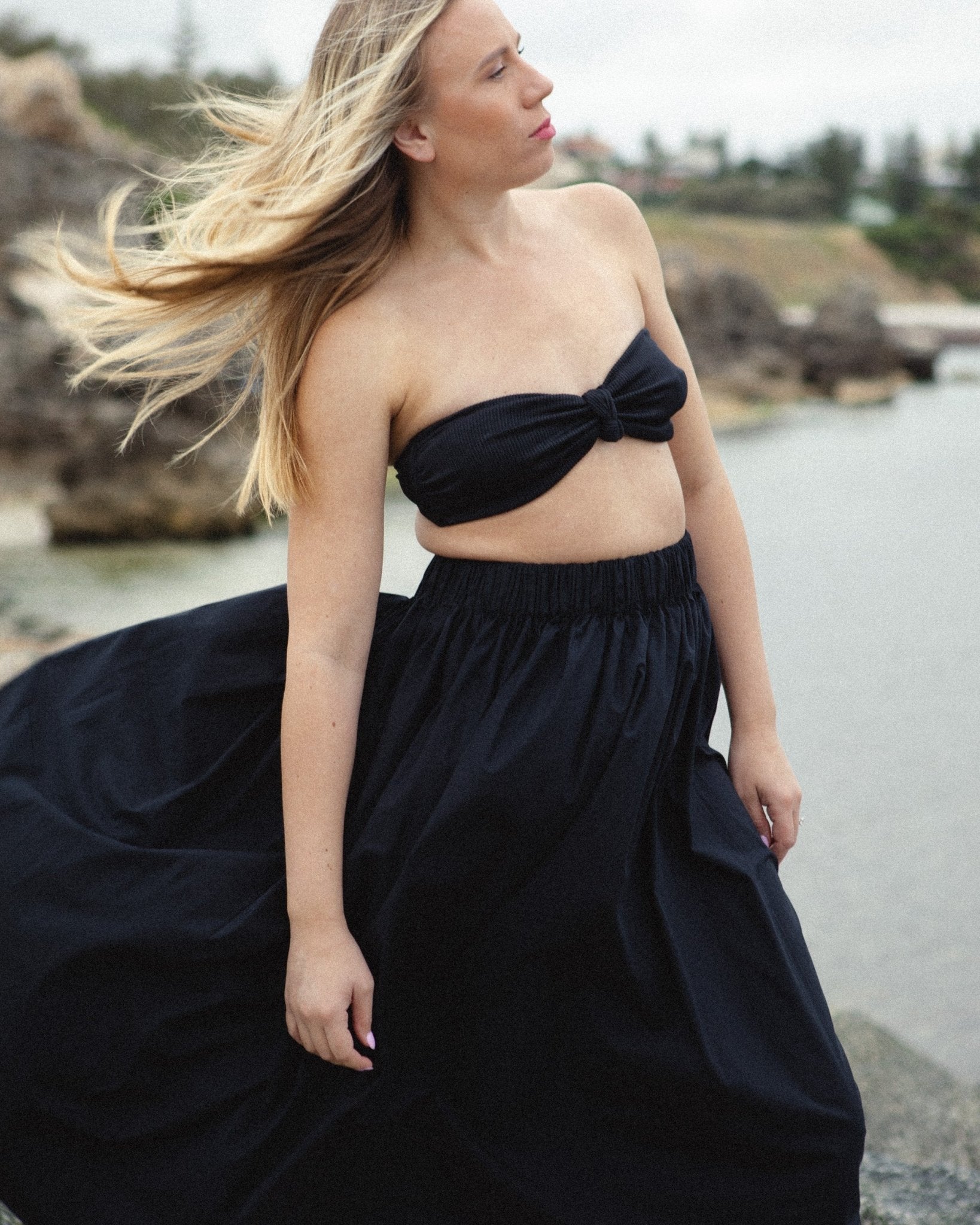 Woman wearing a jet black Gathered Waist Skirt with a bathing top near ocean and cliffs - ANNIE.G
