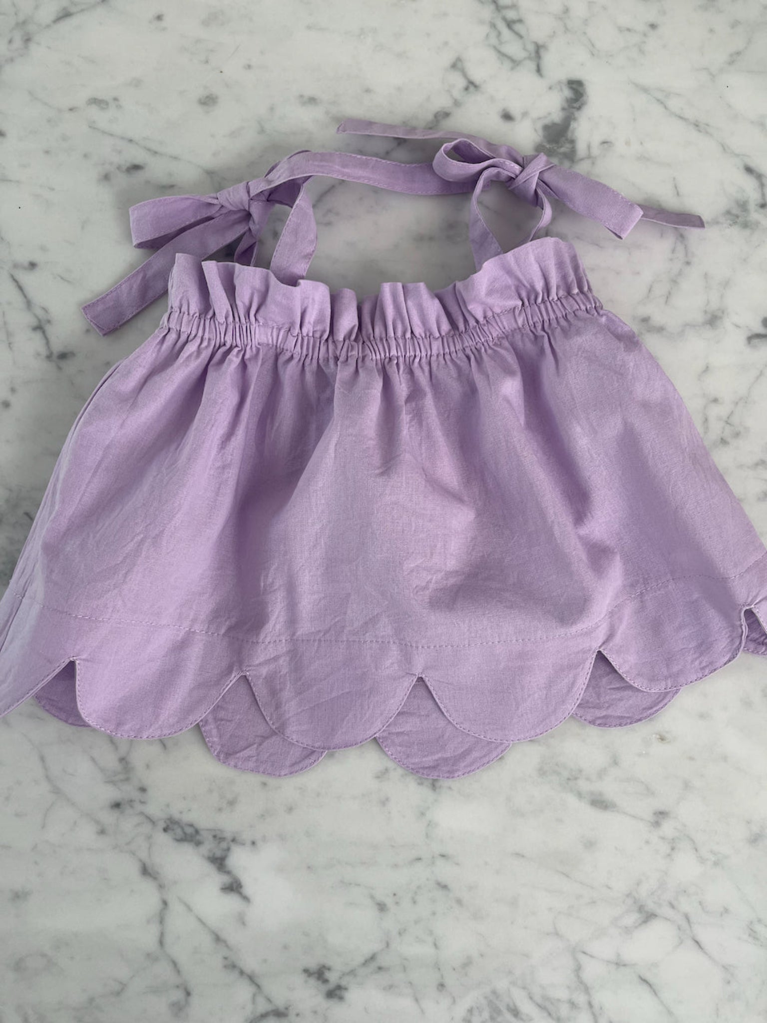 Purple top with shoulder ties and curved hem on bench - ANNIE.G