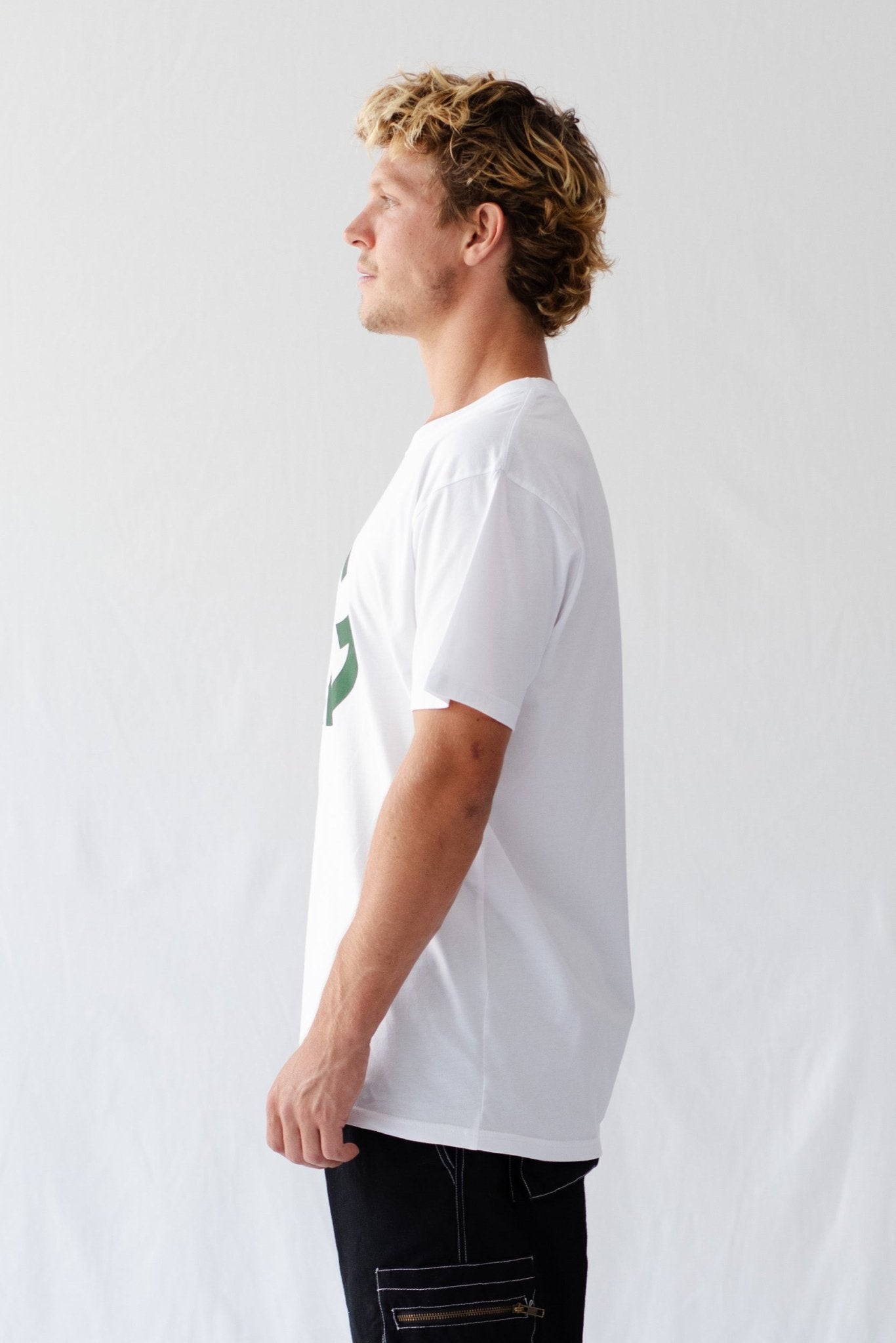 Side of a man wearing a white t-shirt and green 'AG' logo with a running man.