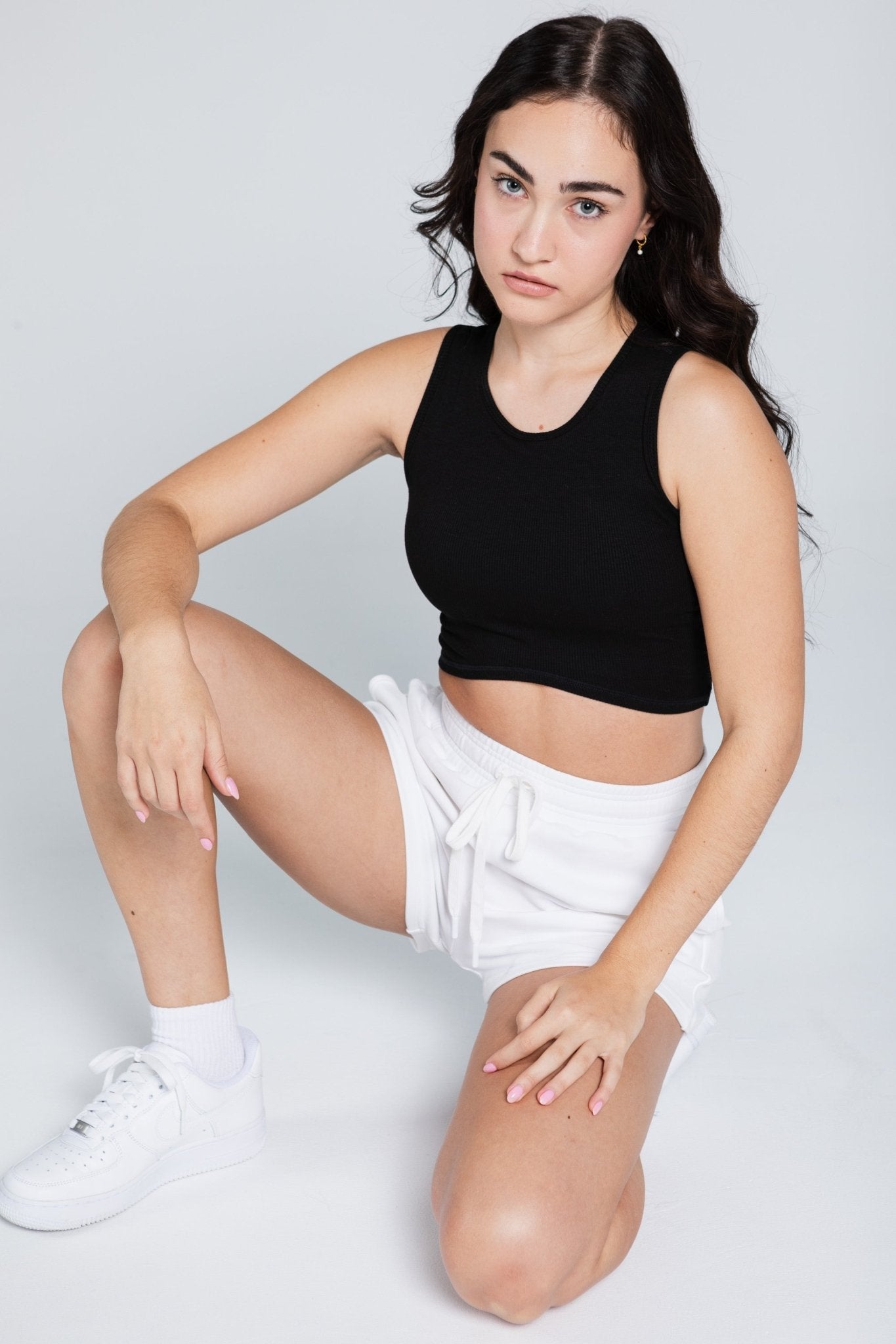 Woman wearing white sweat shorts and black Ribbed Curve crop Tank kneeling down - ANNIE.G