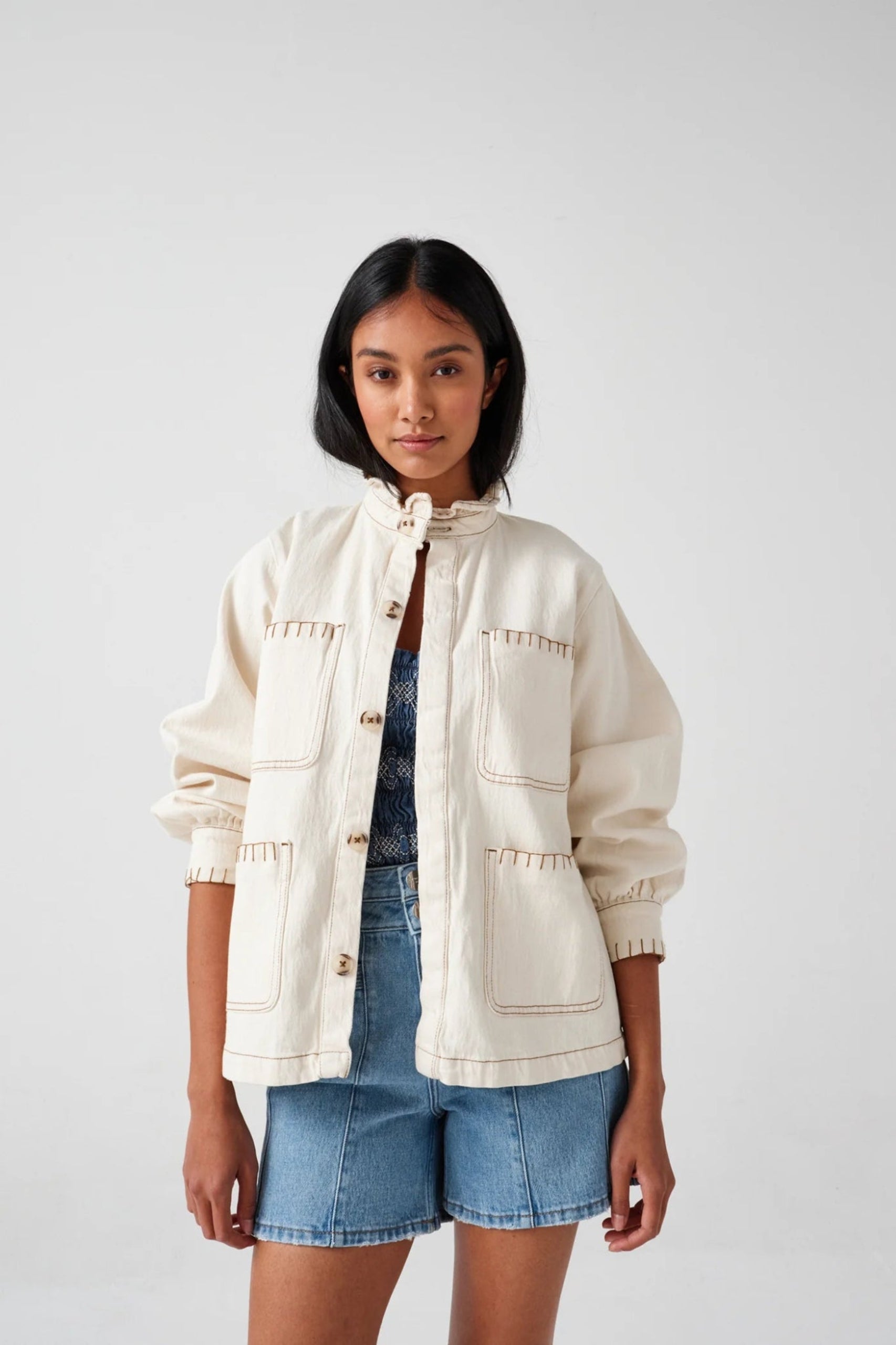 Woman wearing cream jacket and denim shorts - ANNIE.G