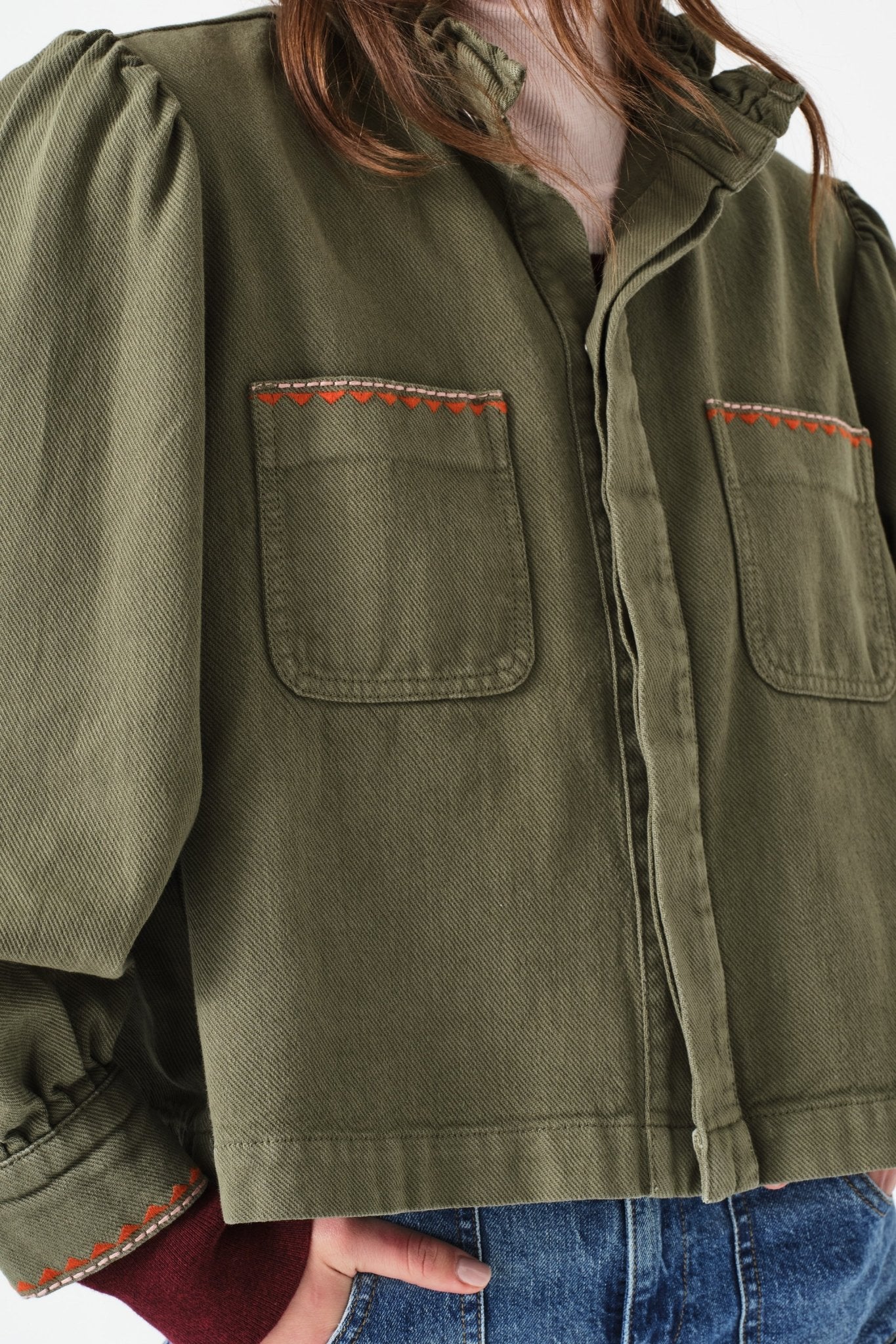Green jacket with front patch pockets with red embroidery at top edge