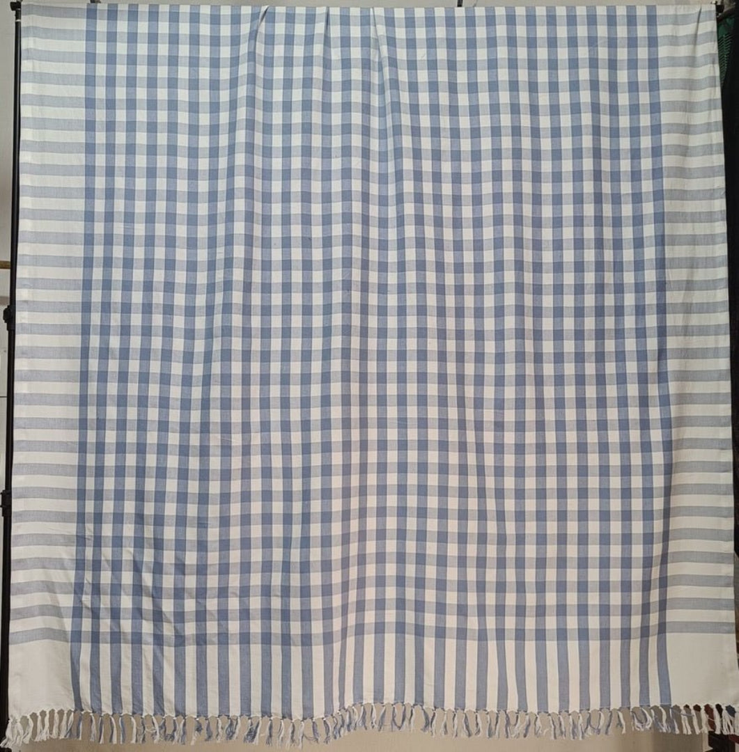 Rectangular light blue checked tablecloth with hand knotted ends hanging over a rail - ANNIE.G