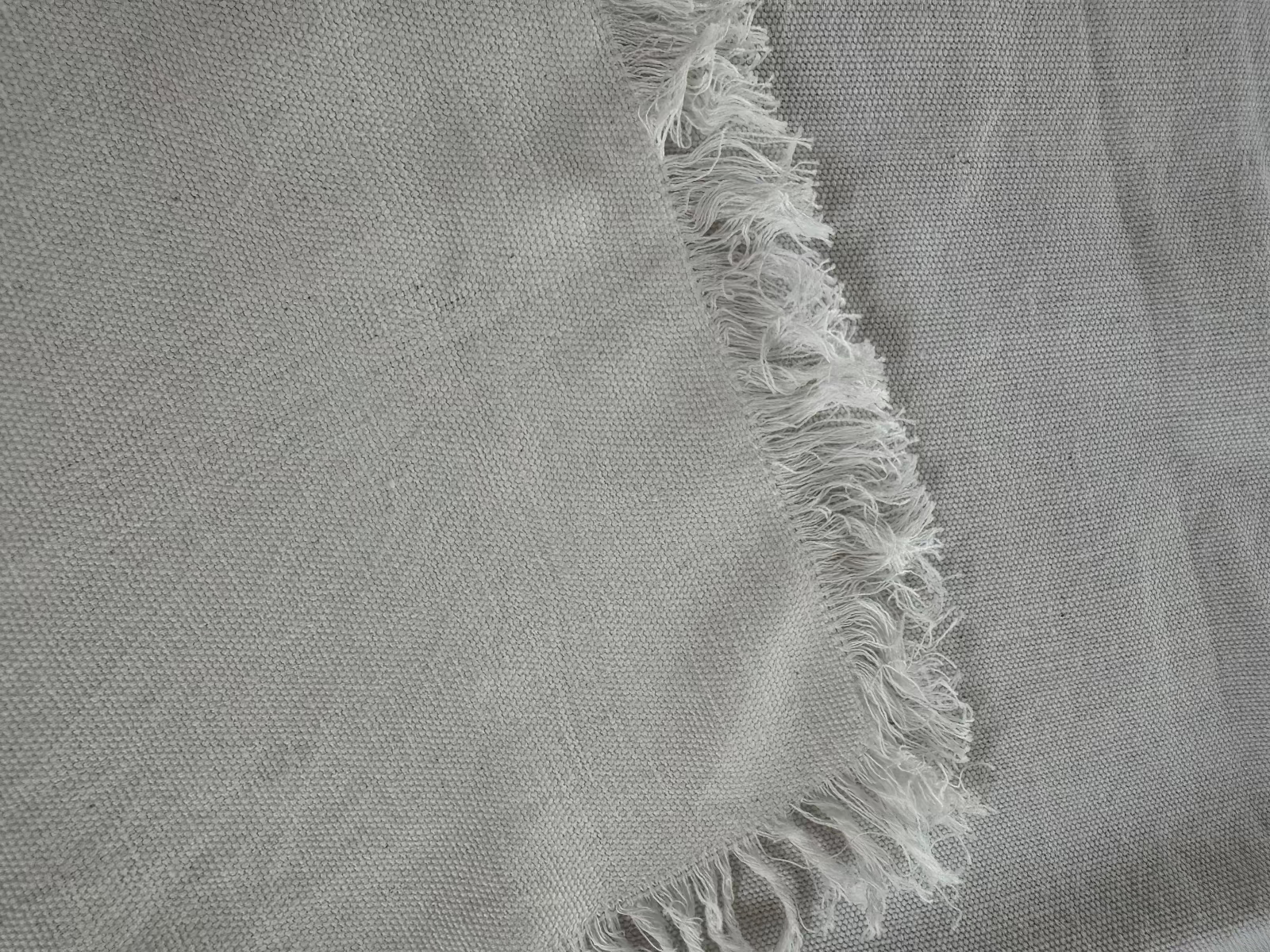 Corner folded over of a white tablecloth with a fringe edge.