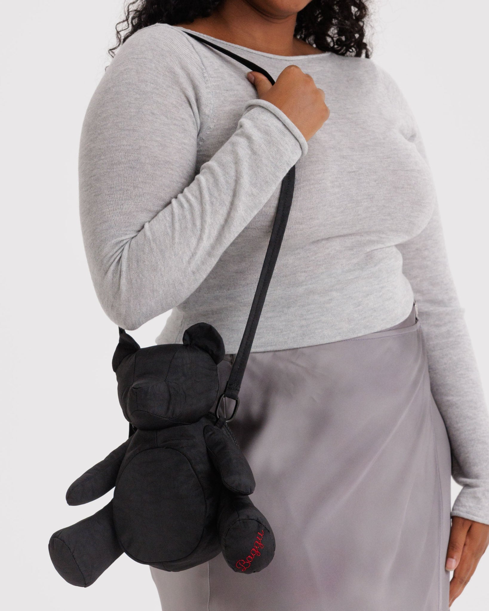 Person wearing a black teddy bear-shaped bag over their shoulder.