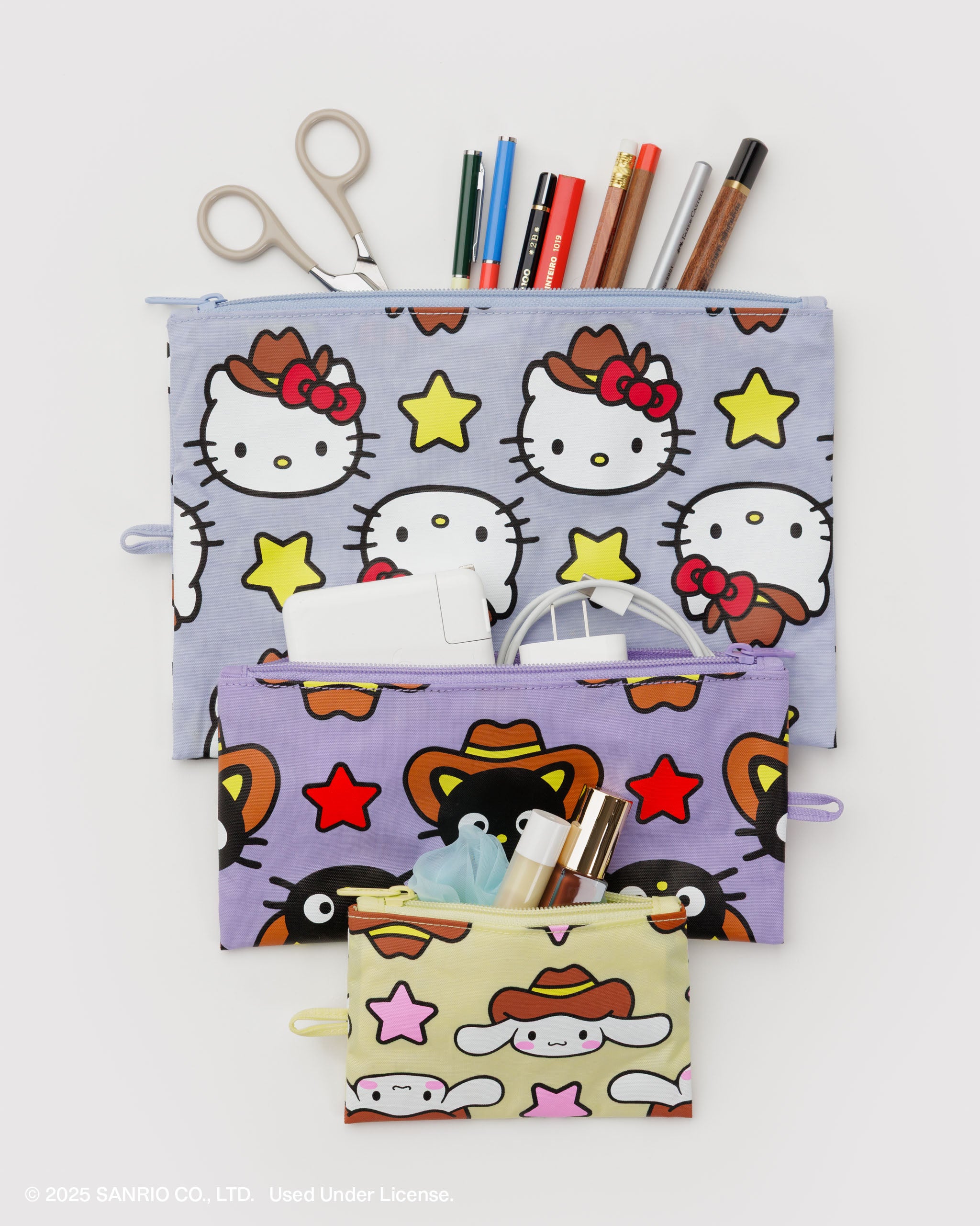 Set of 3 flat pouches of a different sizes in Hello Kitty western design filled with stationery, cords and cosmetics.