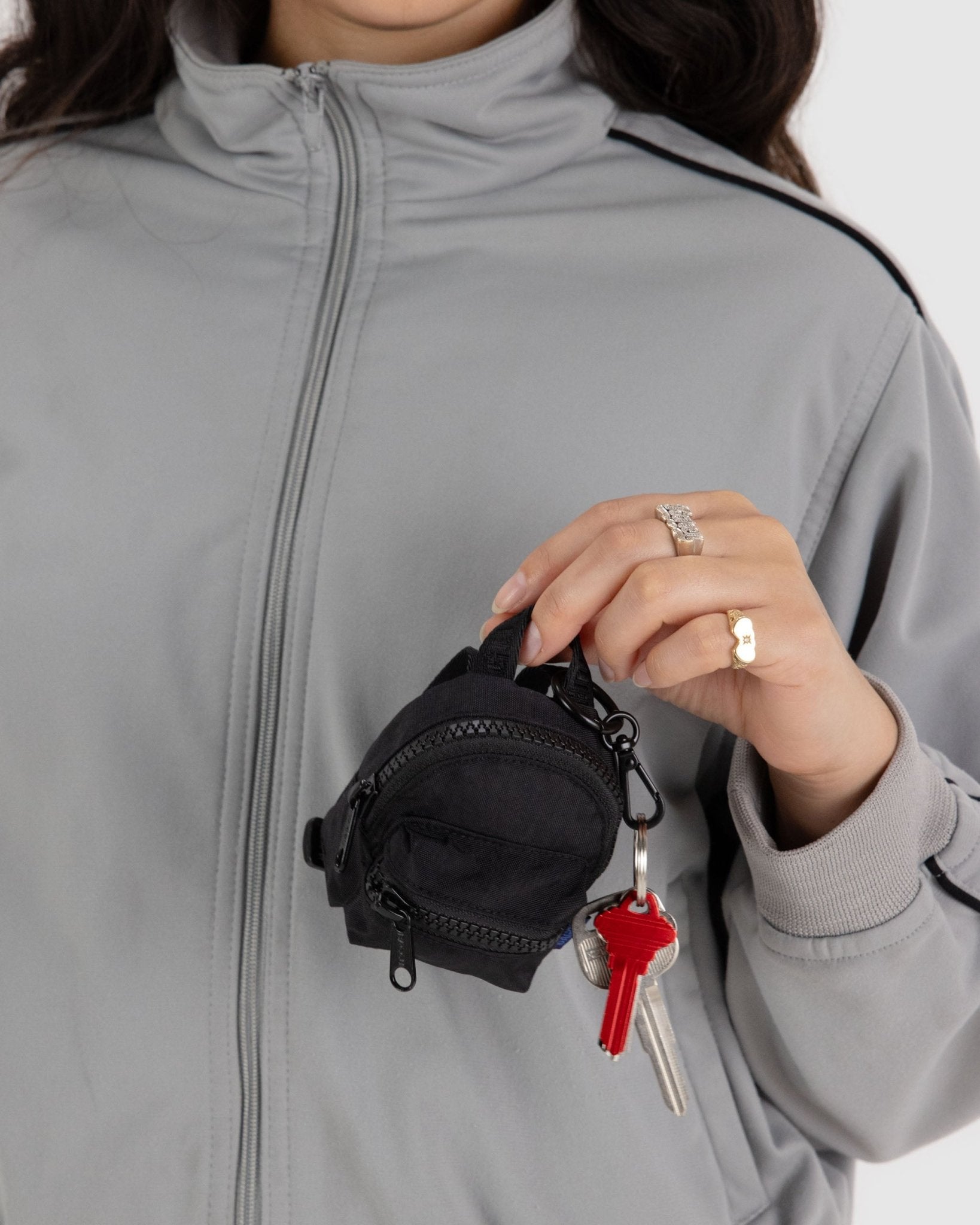 Person holding a black Backpack bag charm with keys attached to keyring - ANNIE.G