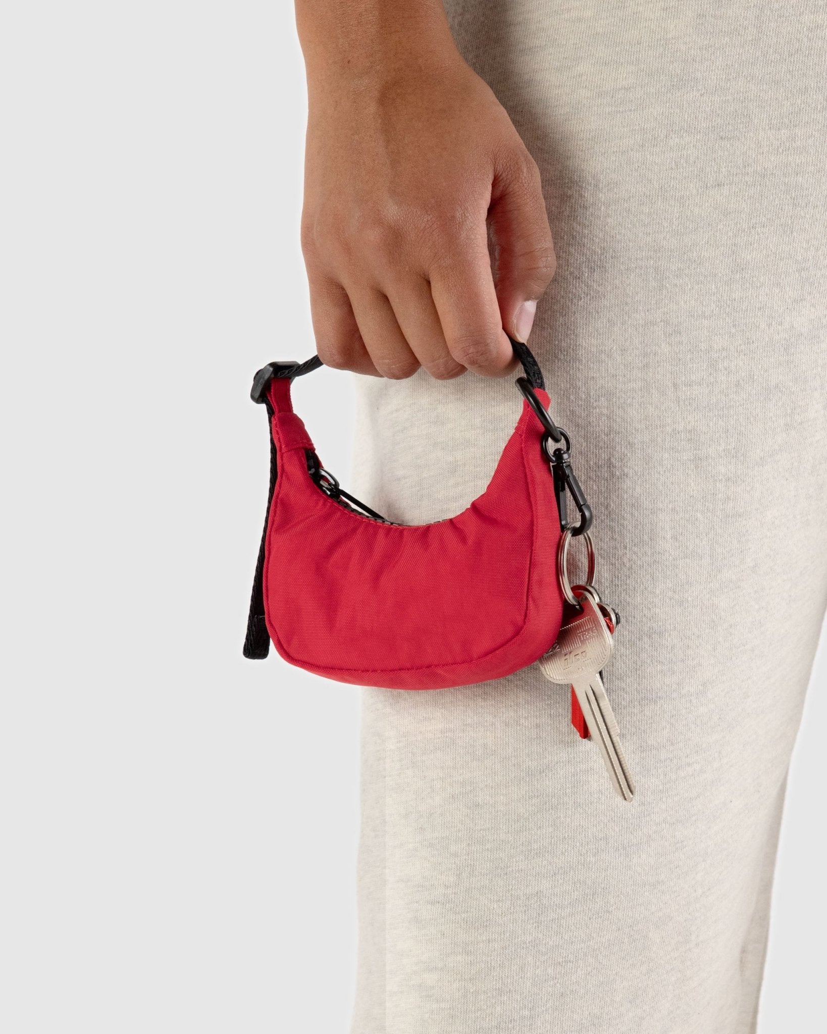 Person holding a handle of red crescent shaped bag charm with keys attached - ANNIE.G