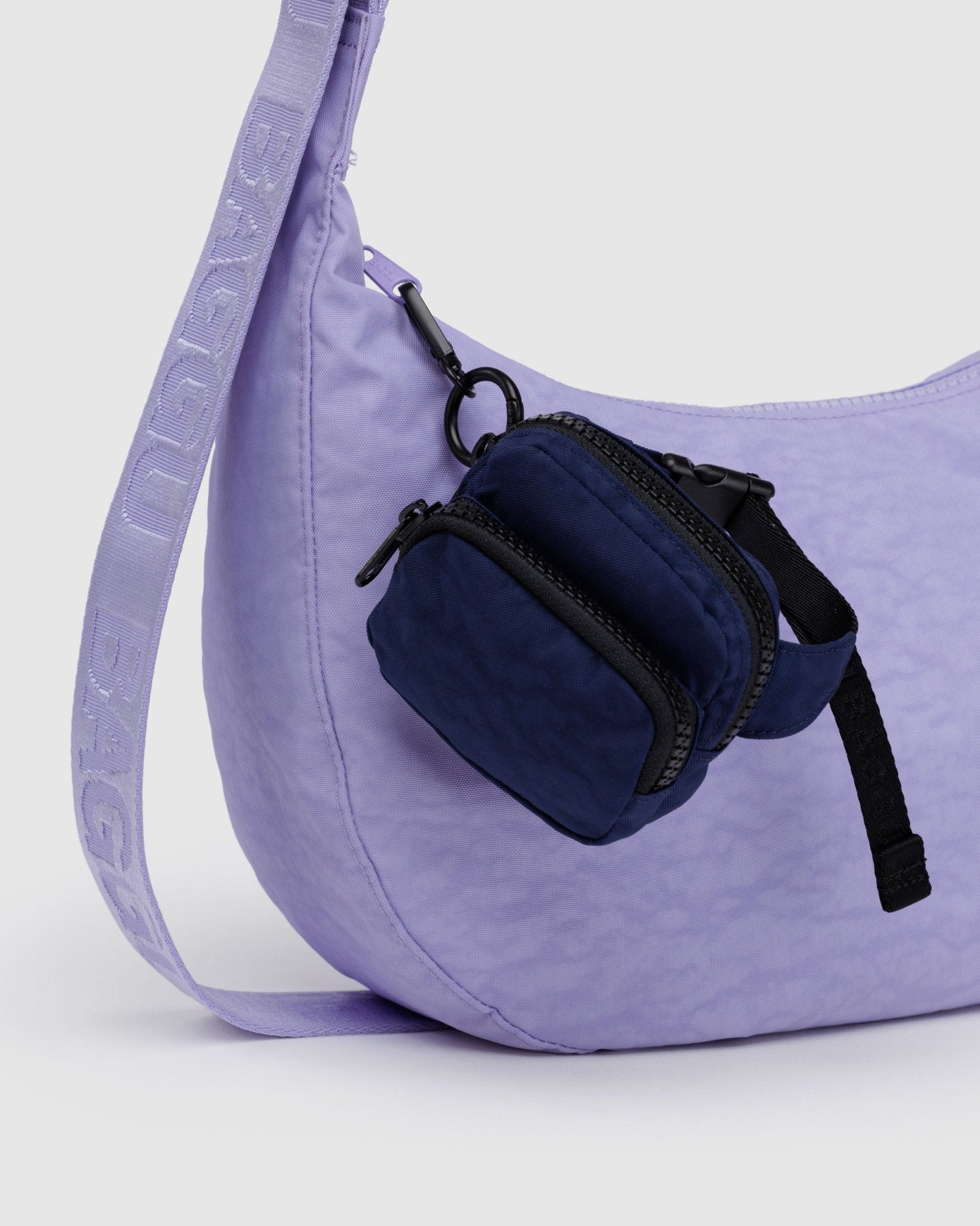 Baggu Fanny Pack Charm with two pockets in Navy attached to zip of purple medium crescent bag