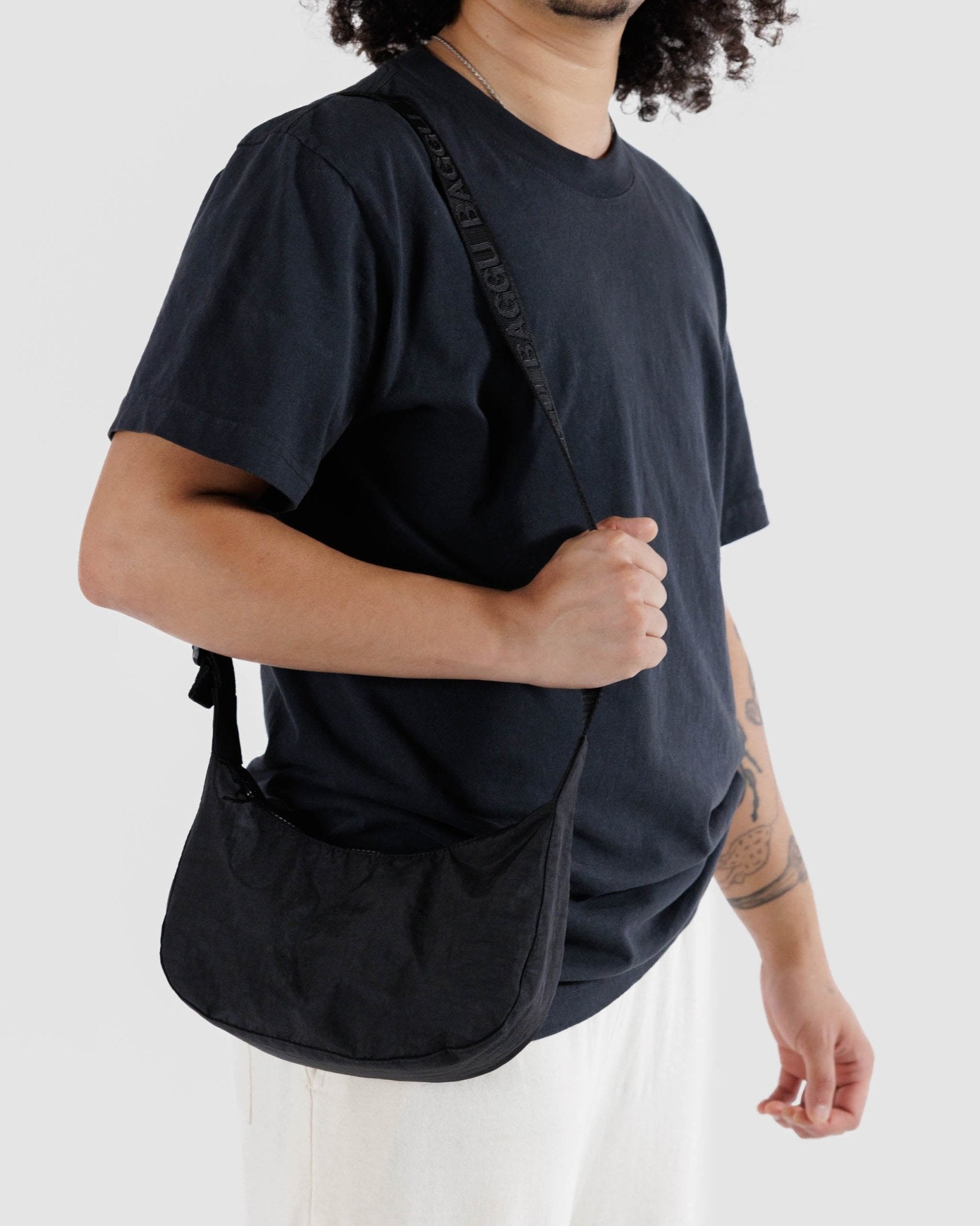 Man carrying a black small nylon crescent bag on shoulder - ANNIE.G