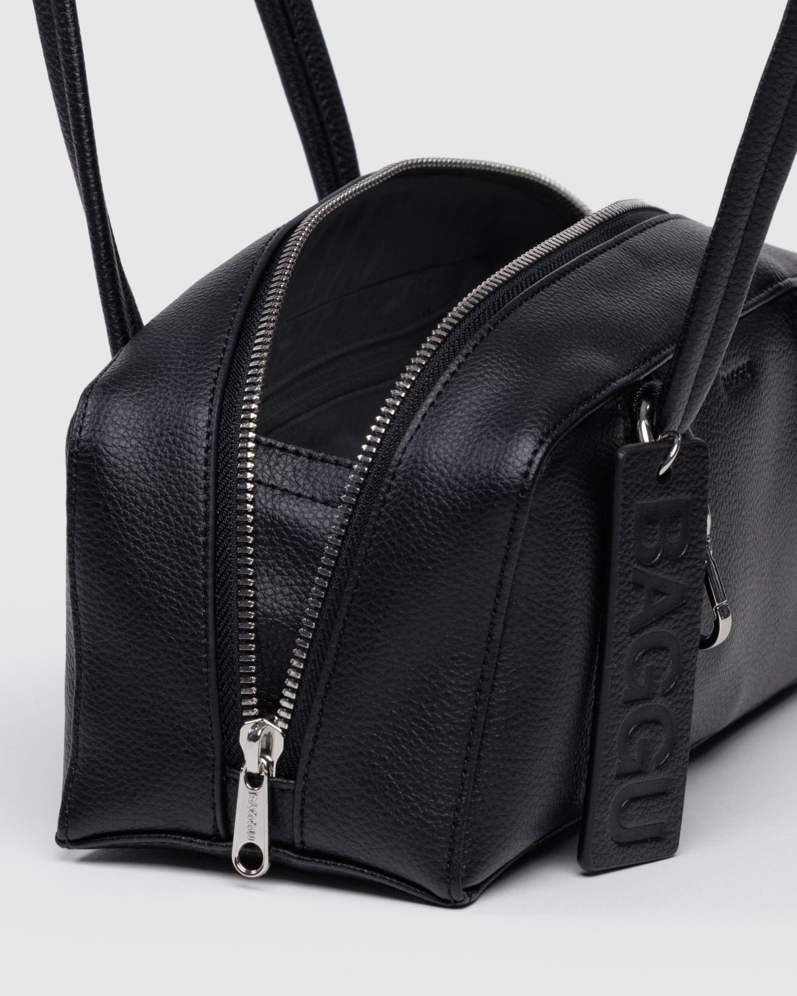 Metal zip open on a black bowler bag with BAGGU leather tag and metal clip on a handle strap.