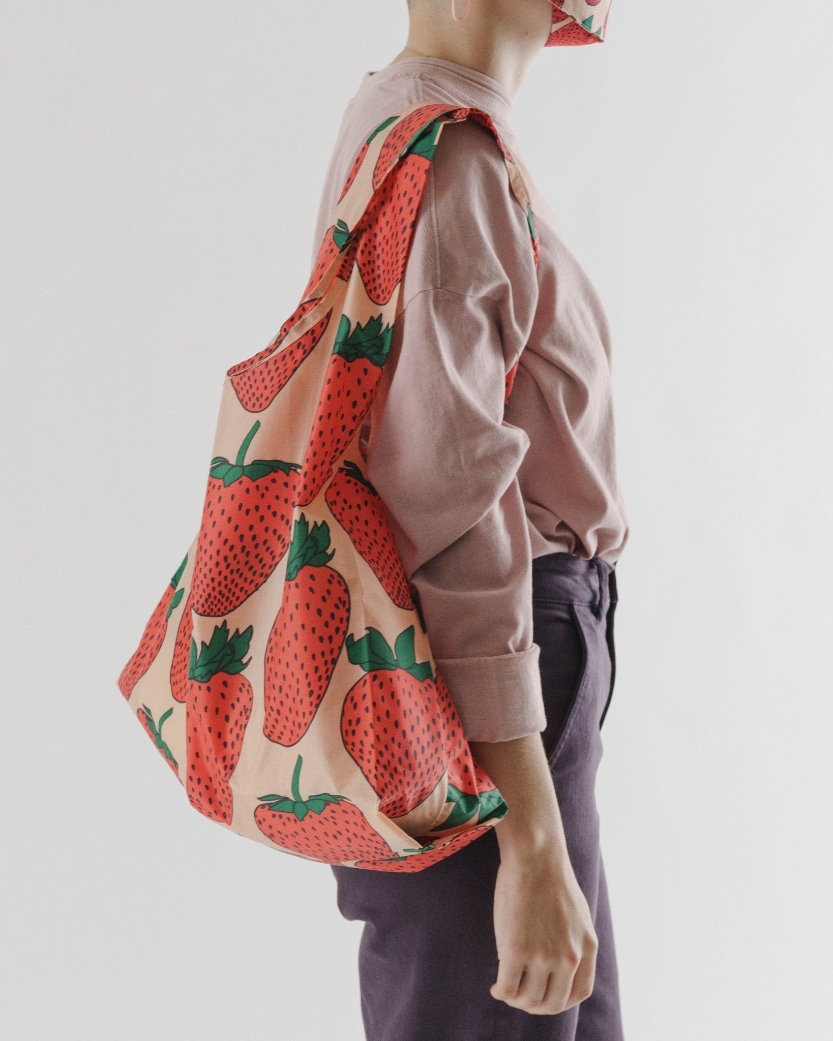 Side view of a person wearing a strawberry print Reusable Bag on shoulder.