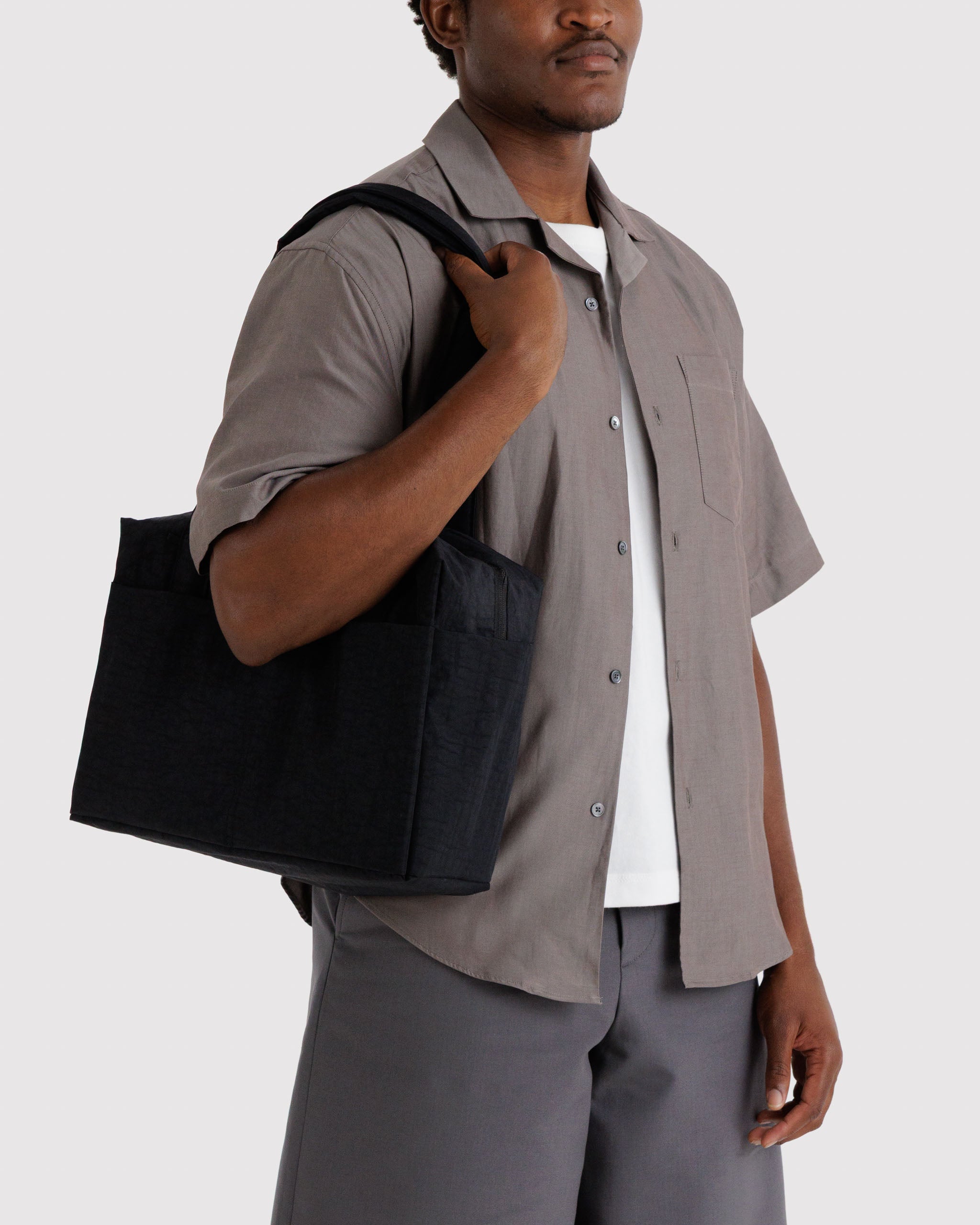 Man carrying a black small duffle bag on shoulder.