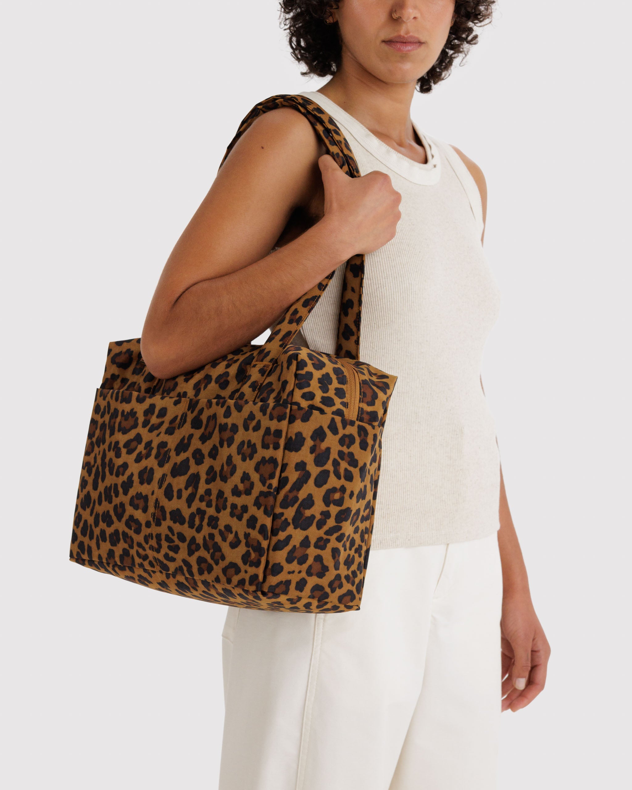 Person holding a leopard print tote bag on shoulder.