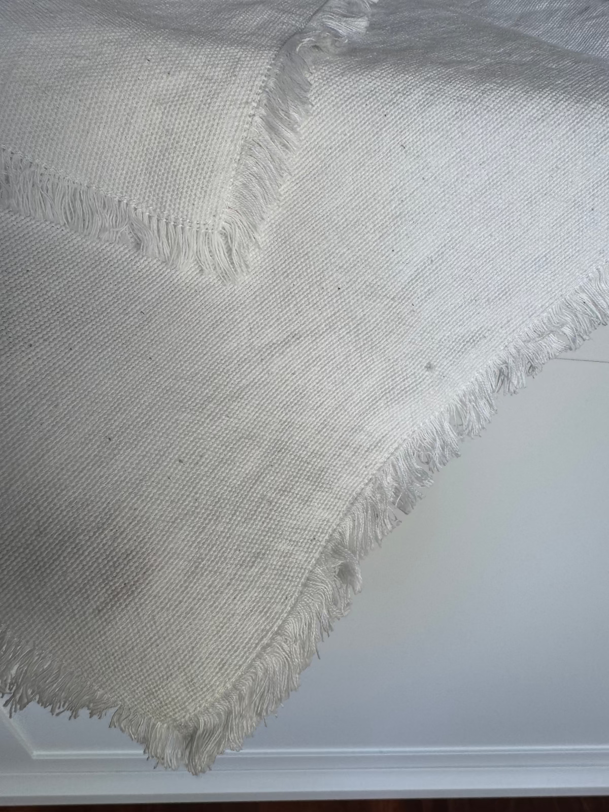 White cotton napkin with frayed edges over the edge of a table