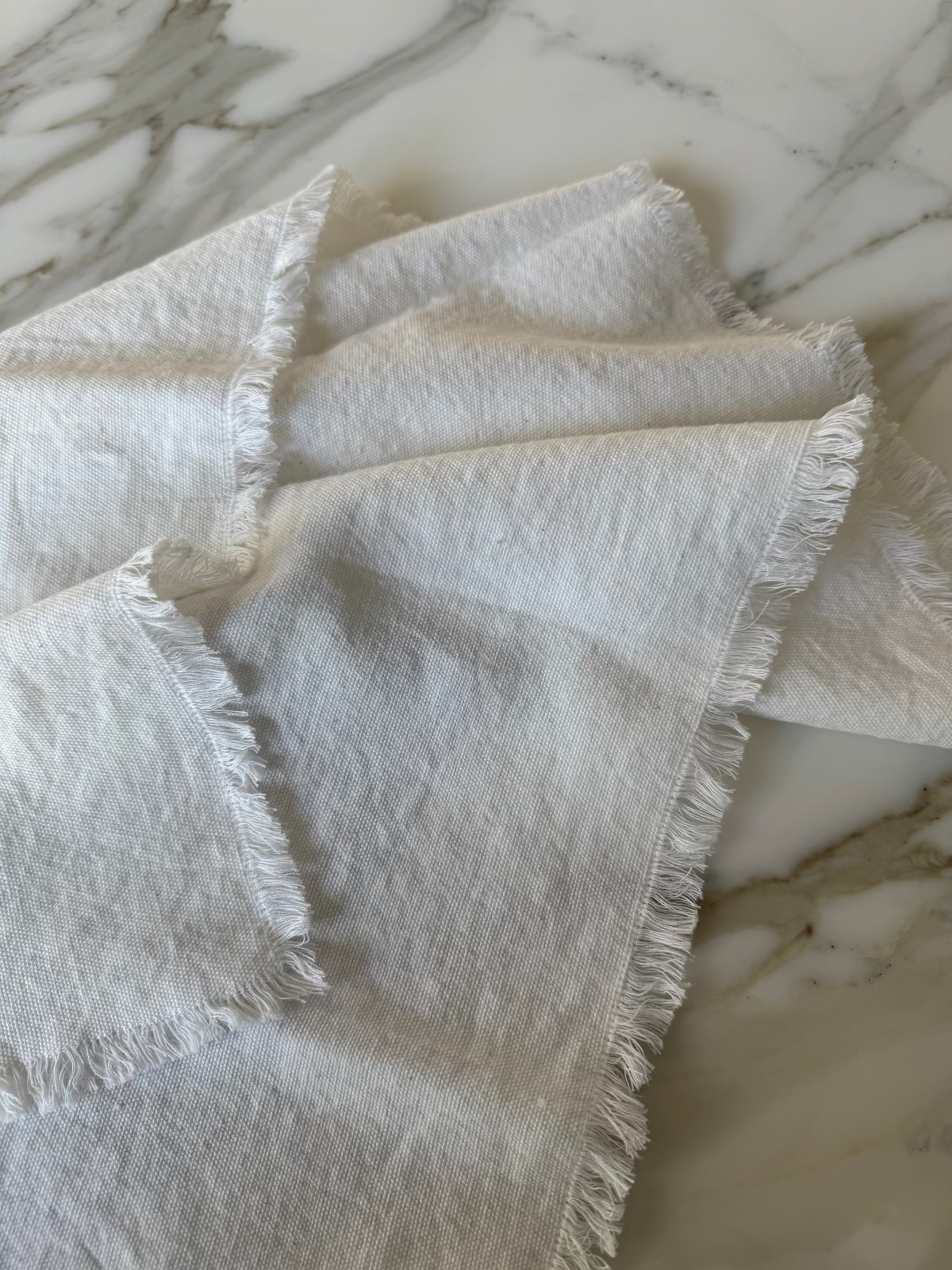 White cotton napkin with frayed edges on a marble surface
