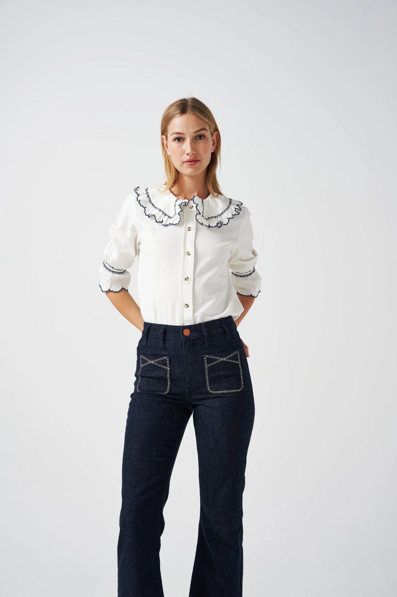 Person wearing a white three quarter sleeve shirt with colar and blue embroidery trim with blue jeans - ANNIE.G