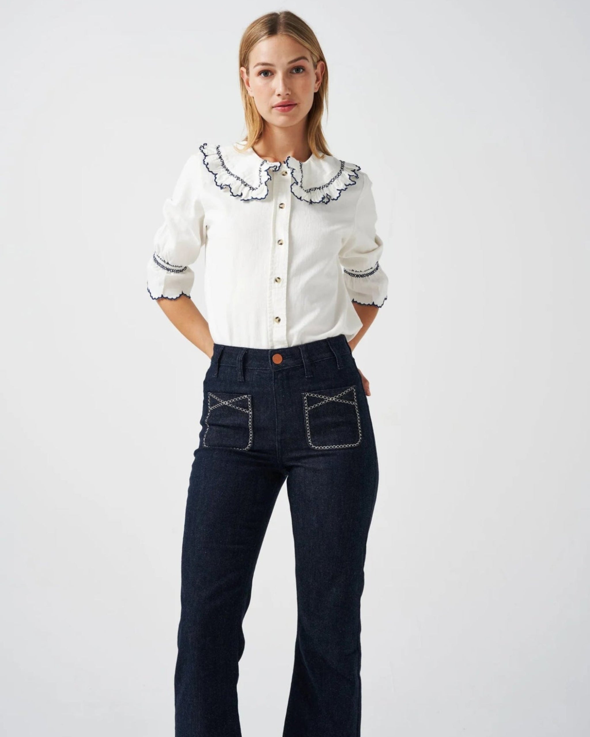 Person wearing a white three quarter sleeve shirt with collar and blue embroidery trim with blue jeans - ANNIE.G