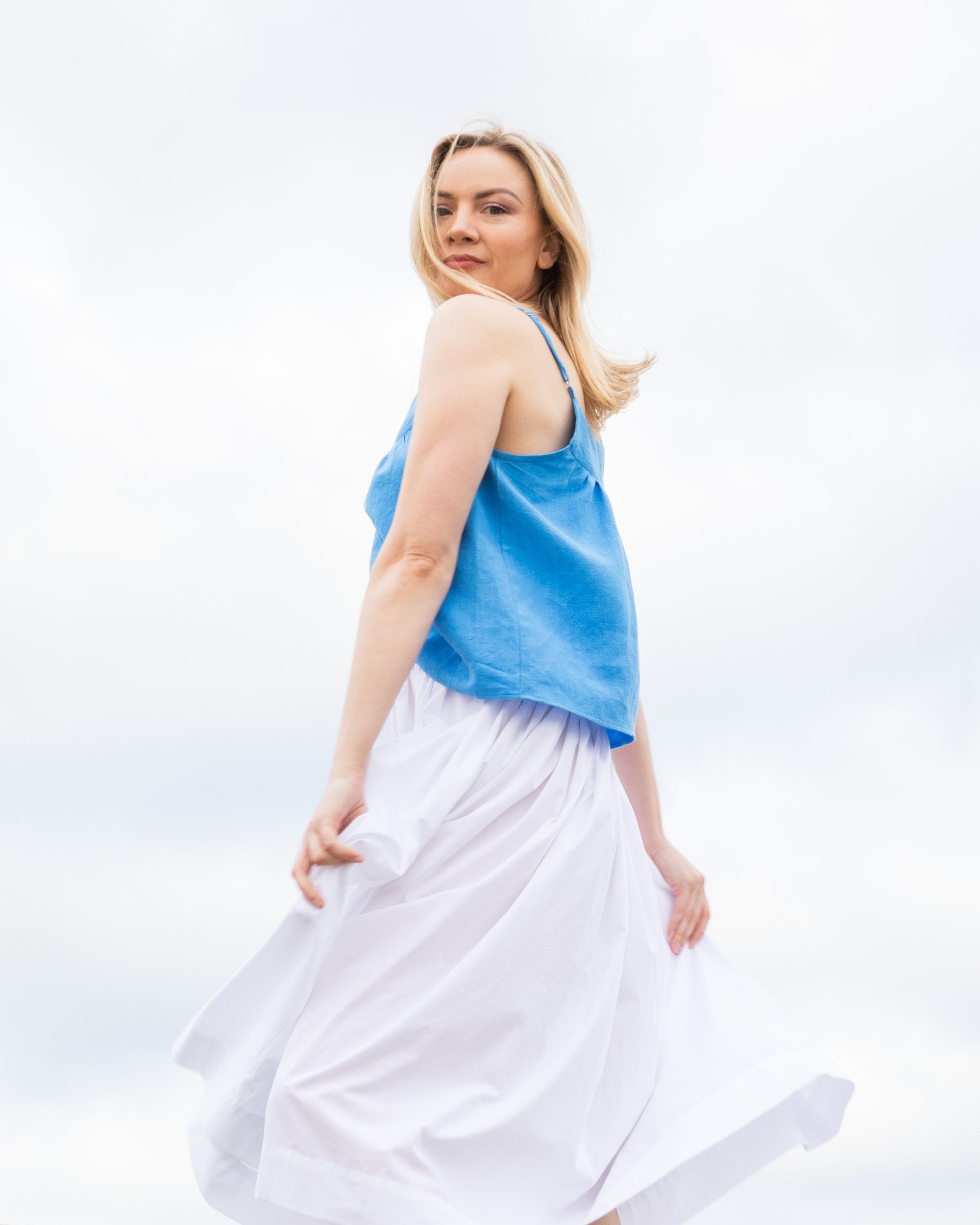 woman-twirling-in-gathered-waist-skirt-white-and-blue-cami-top