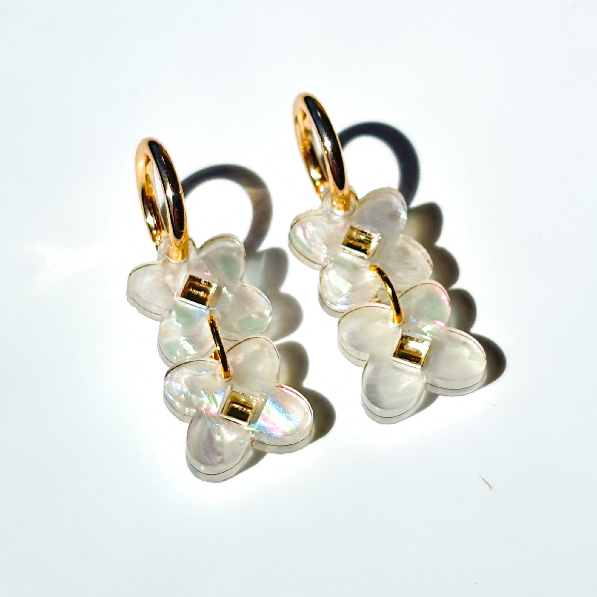 Two sweet clover acrylic flowers inset with gold mirror diamond in white swirl acrylic on small gold hoops.
