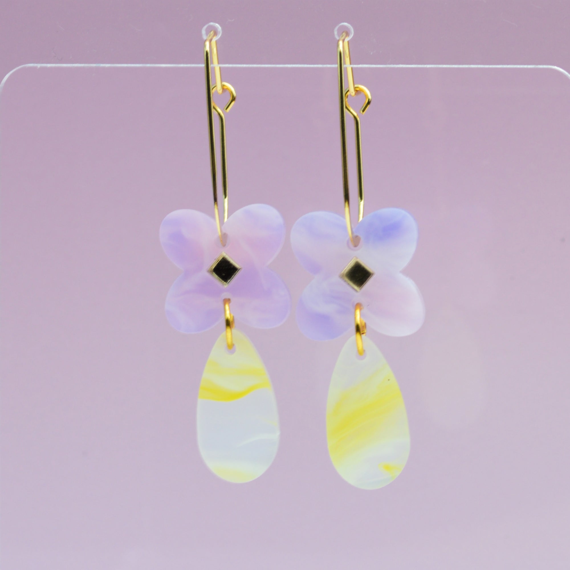 Drop earring in acrylic clover flower in lavender swirl colour with mirror diamond centre and tear drop attached in yellow and white swirl colours.