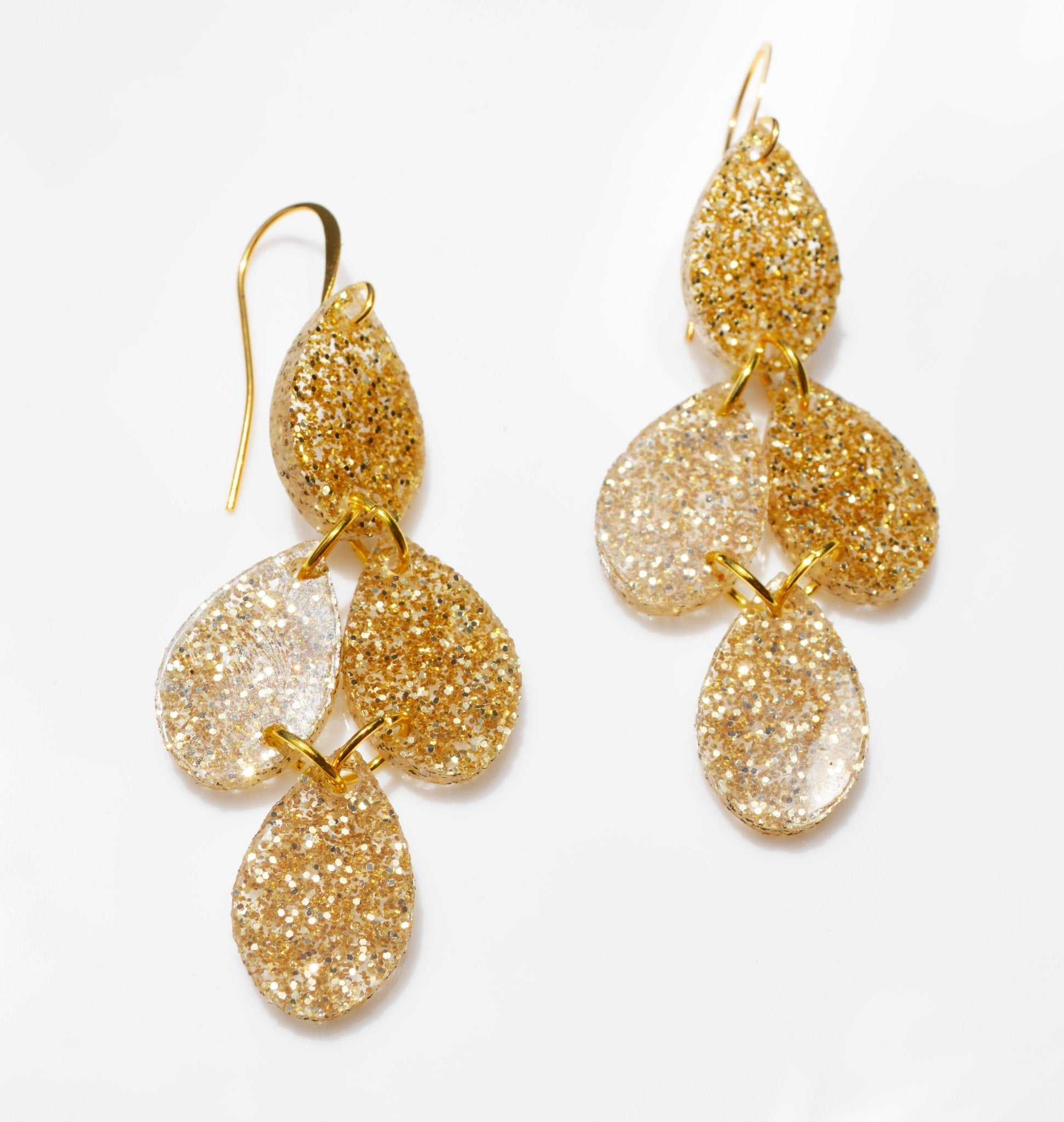 Gold sparkly acrylic dangle earrings in drop shape joined in a chandelier shape on a gold hook.