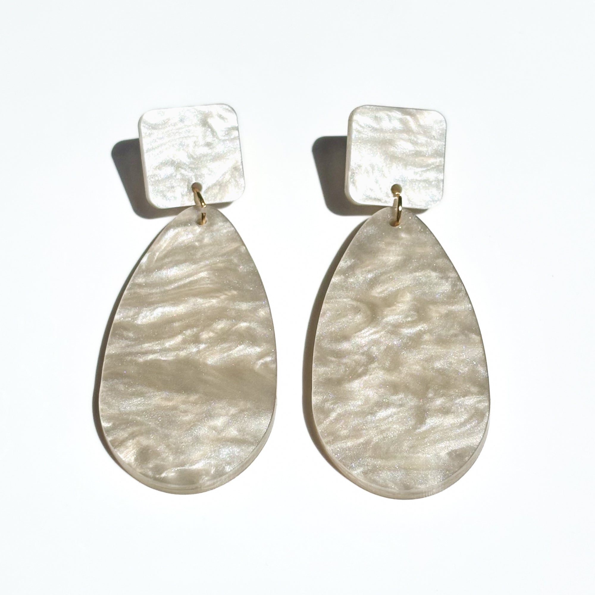 Pearl colour acrylic dangle earrings with square shape at the top and a large tear drop shape attached.