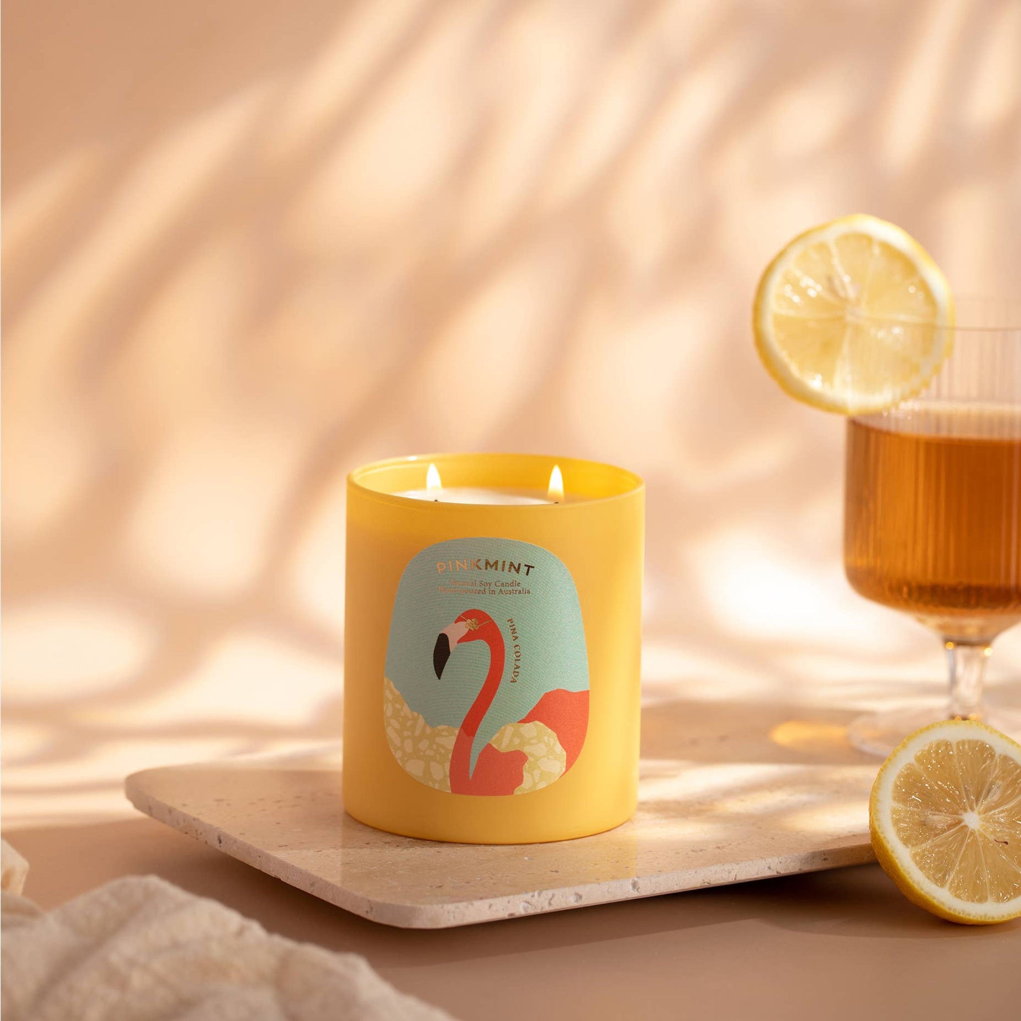 Yellow jar candle with a yellow drink in a glass and a lemon beside - ANNIE.G