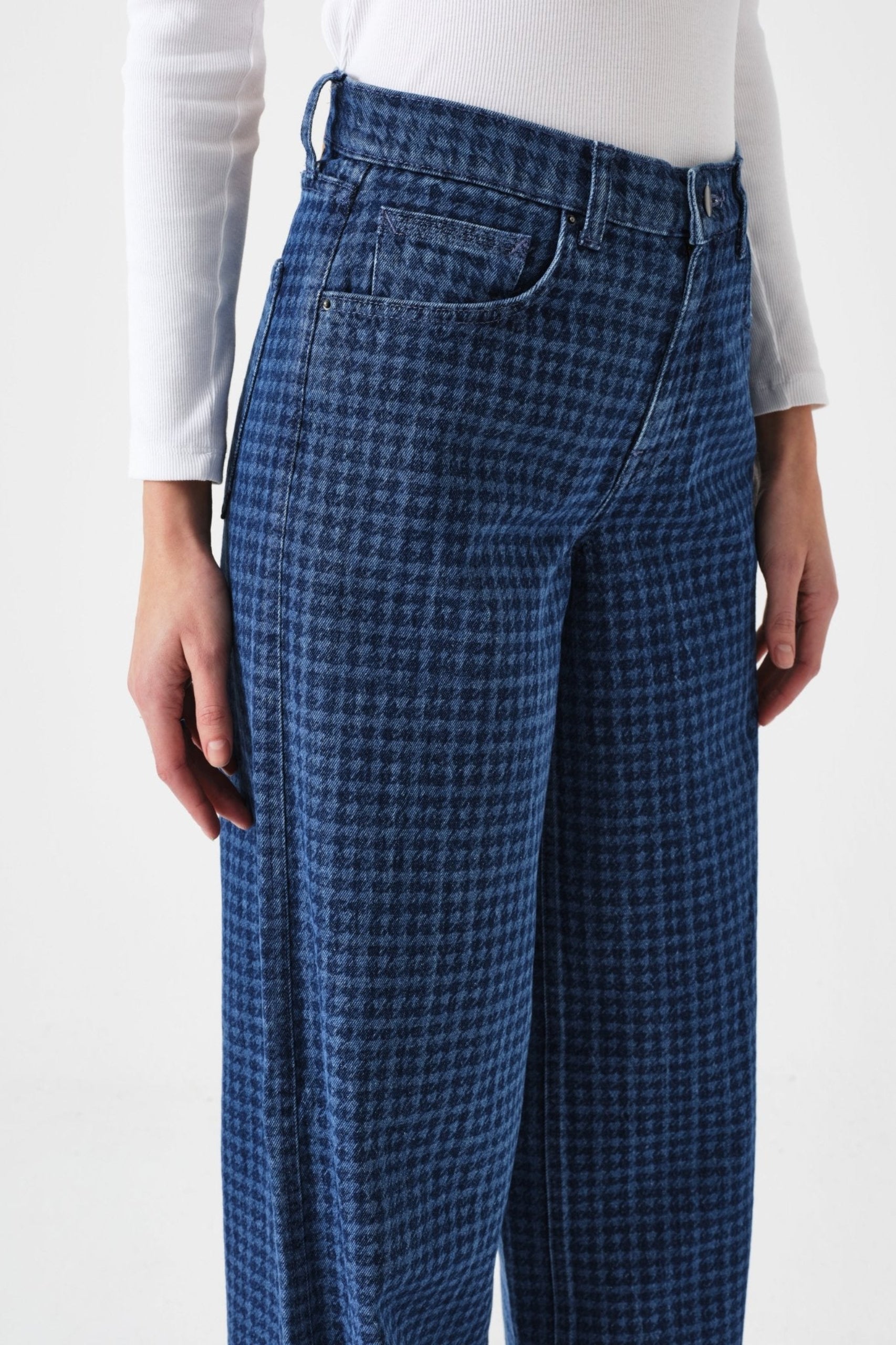 Close up of blue checkered pants with pockets worn by a woman with a long sleeve white tee.