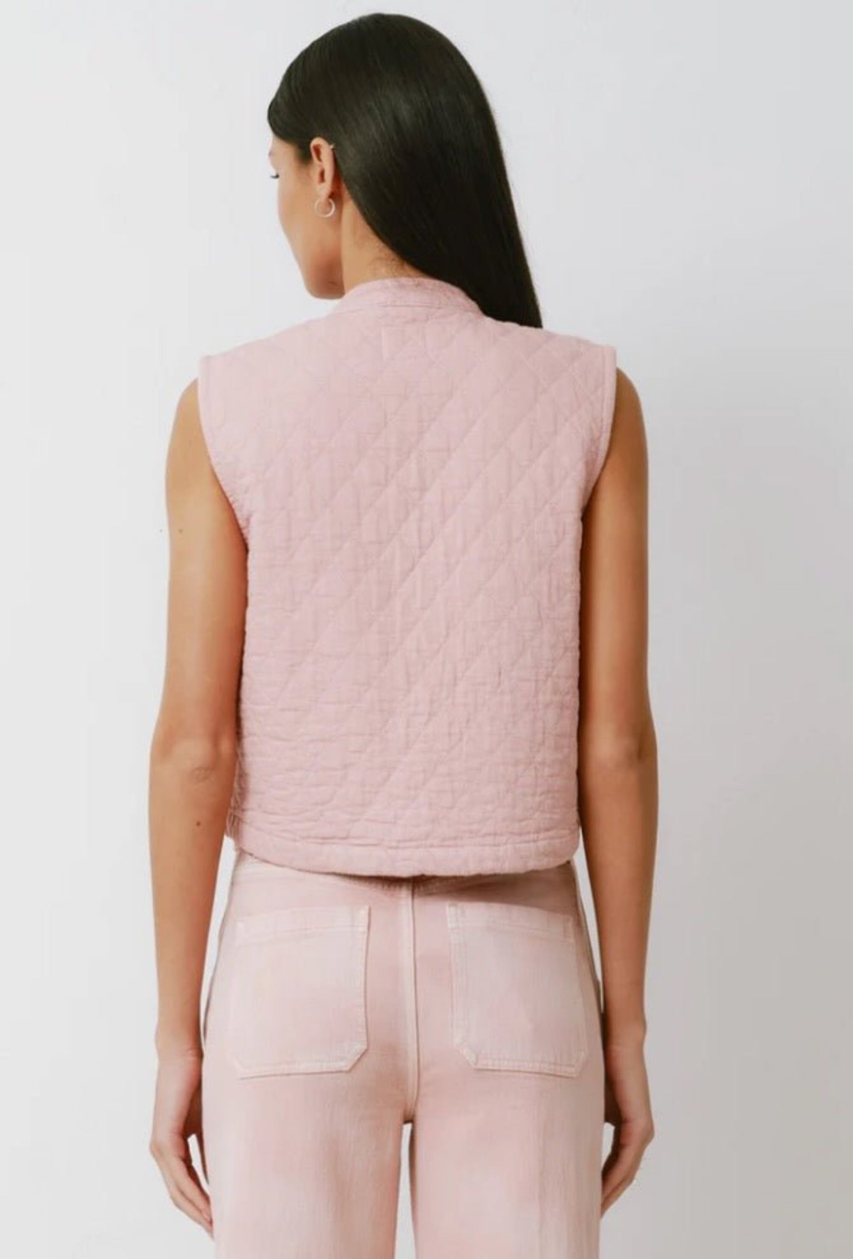 Back of a woman wearing a pink quilted vest and pink pants.