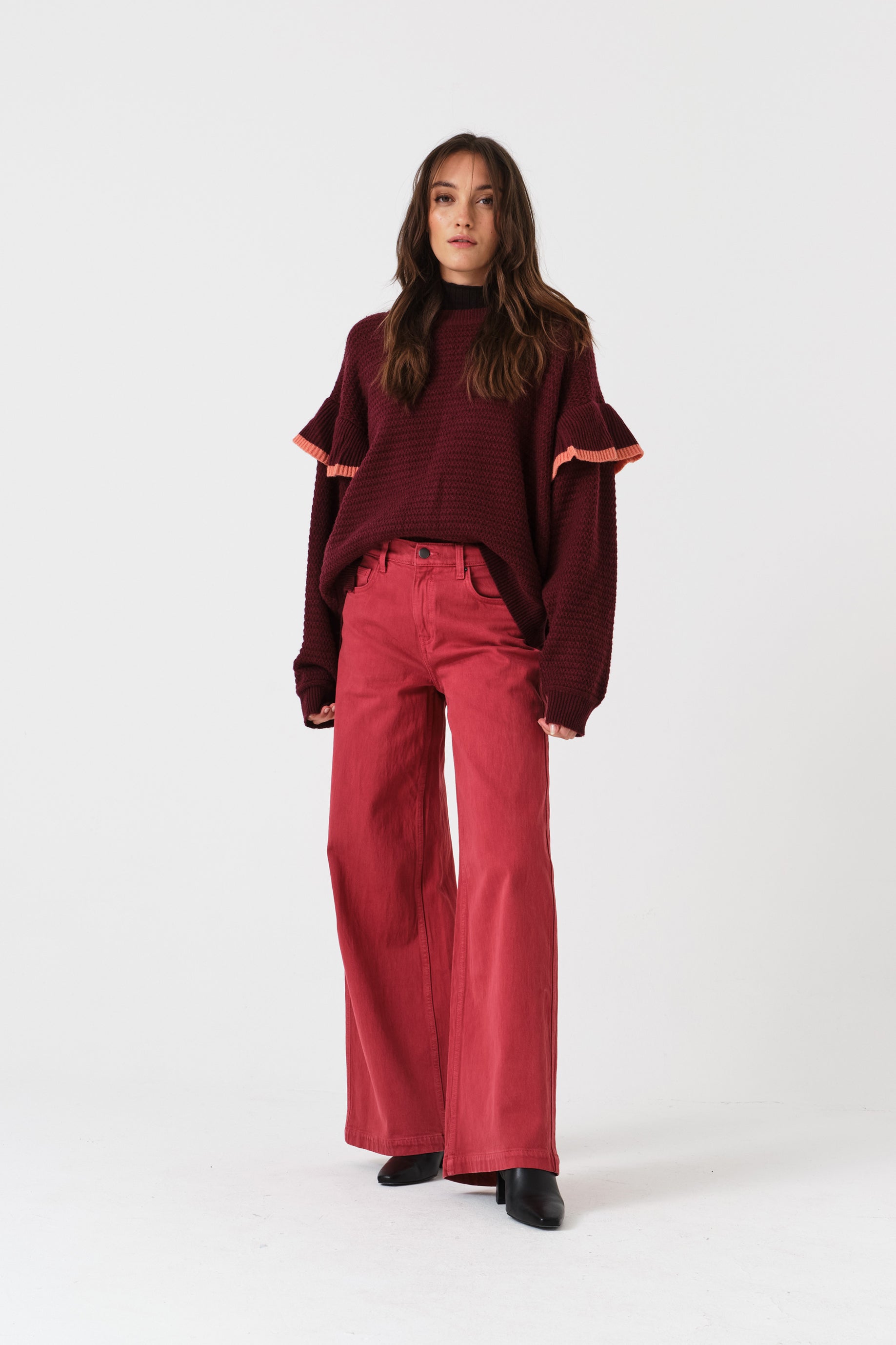 Woman wearing a burgundy sweater and faded rose denim jeans pants.