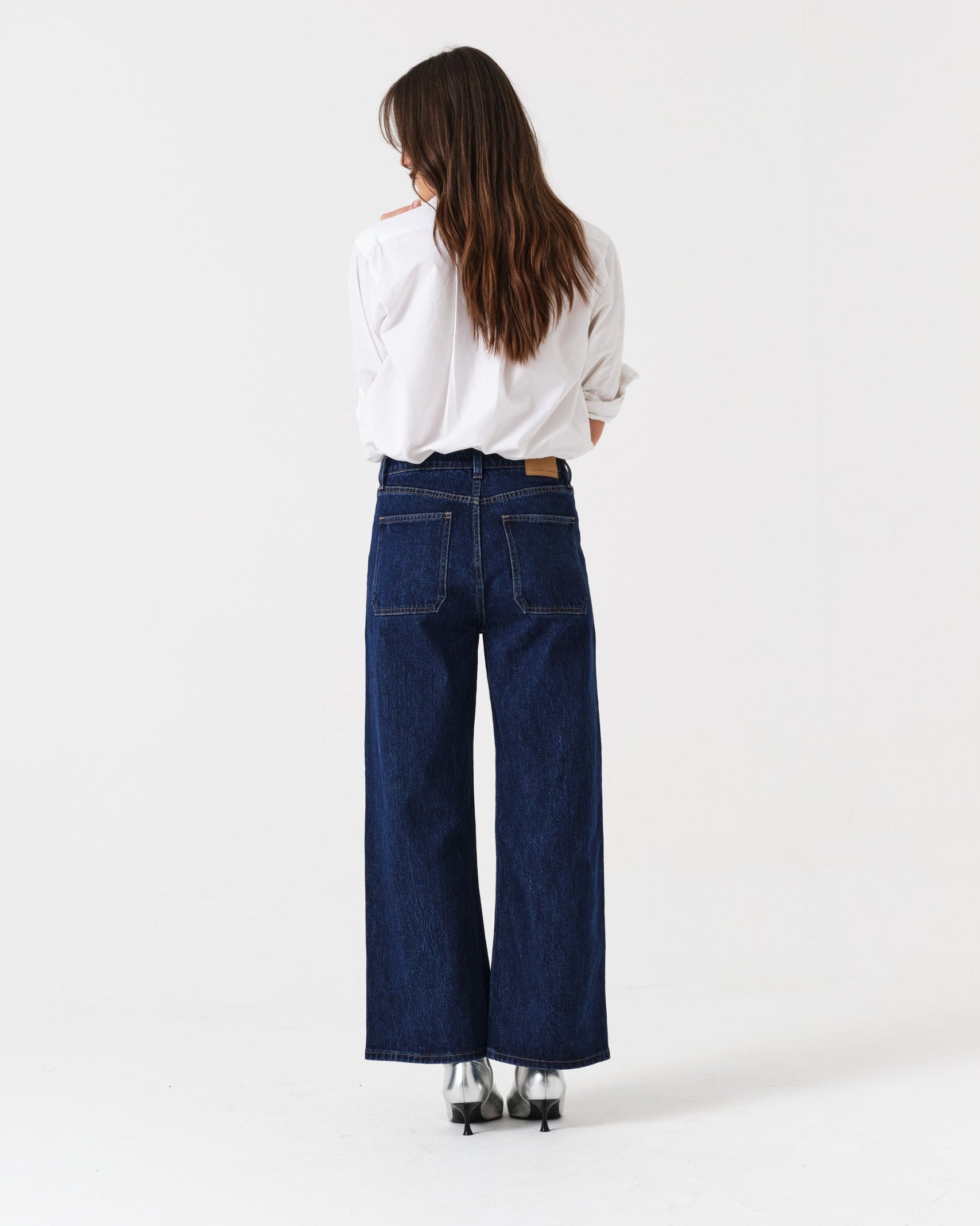 Back of a person wearing blue cropped jeans and a white shirt.