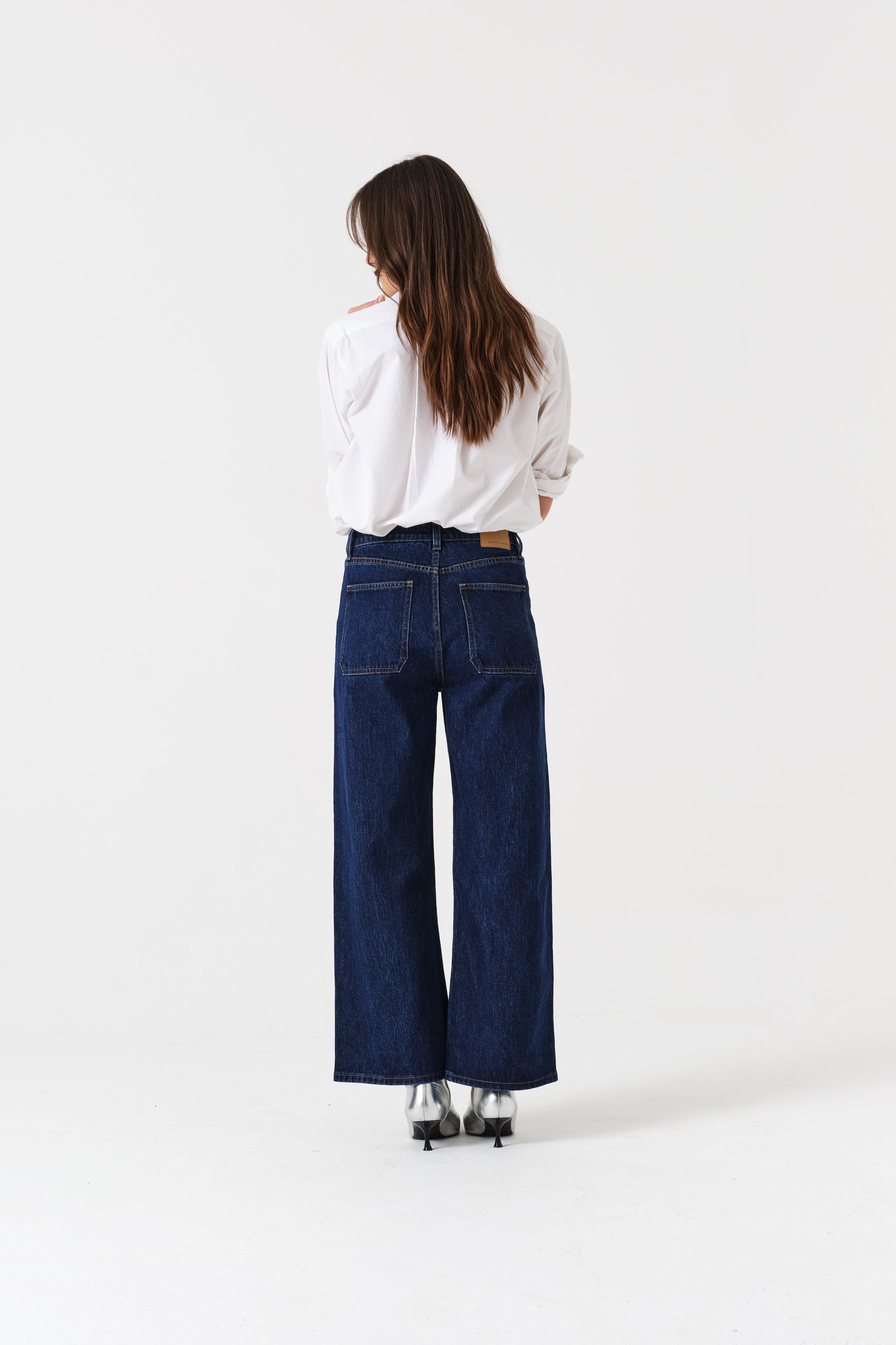 Back of a person wearing blue cropped jeans and a white shirt.