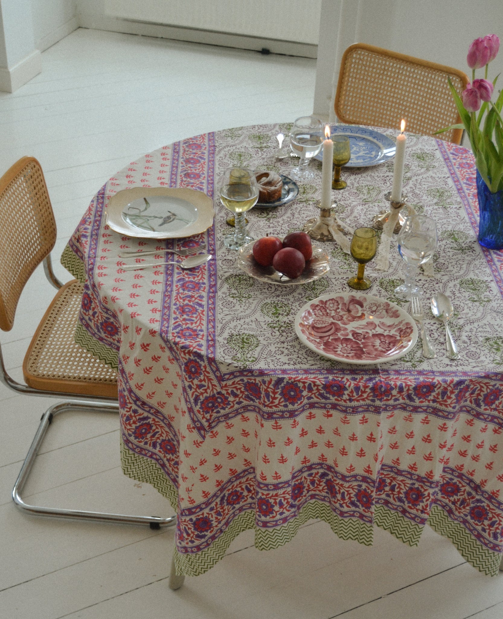 Cream background with green, pink patterns and purple flower cotton tablecloth set on a round table.