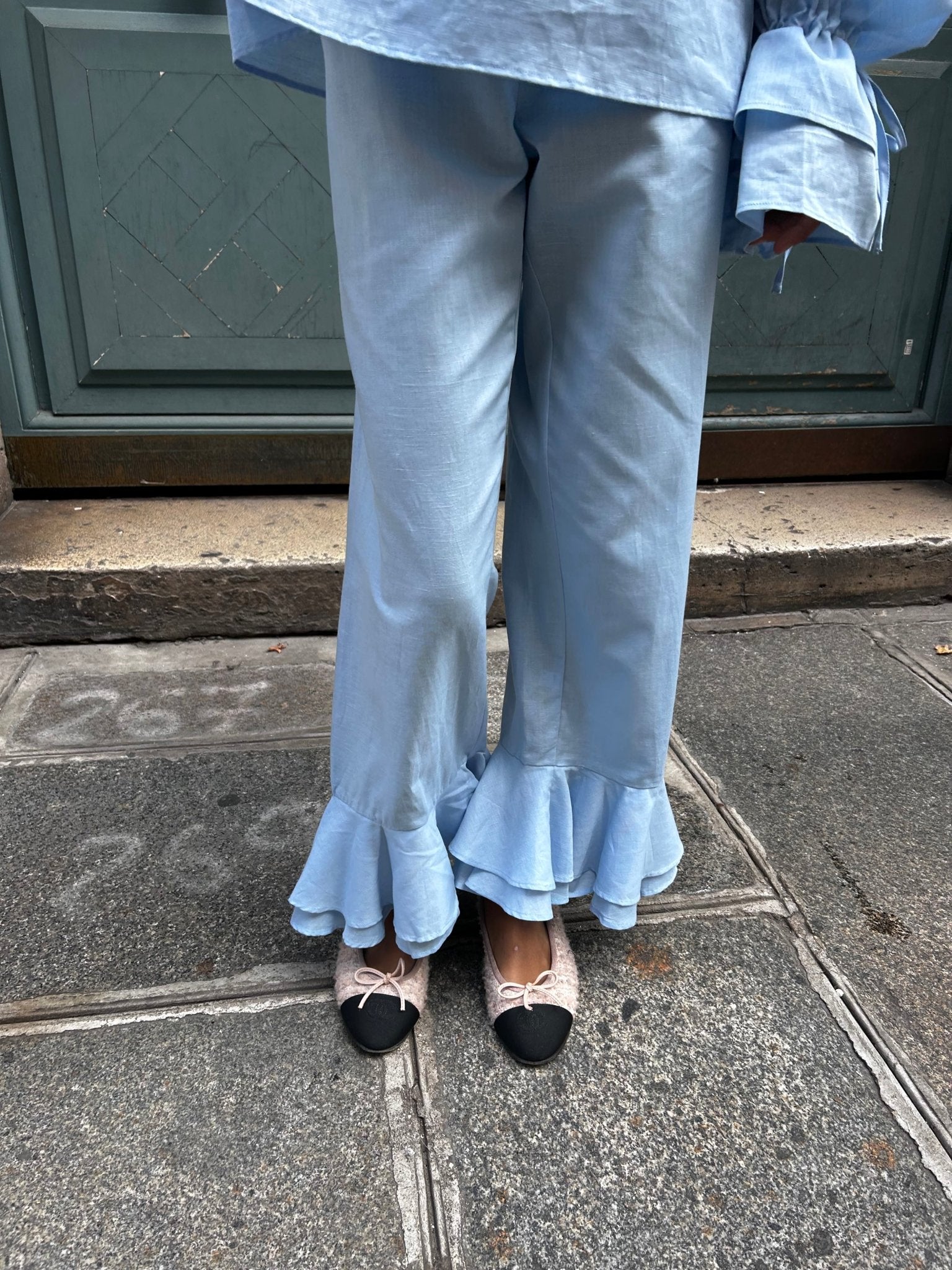 Person wearing blue linen lounge pants with frill cuff