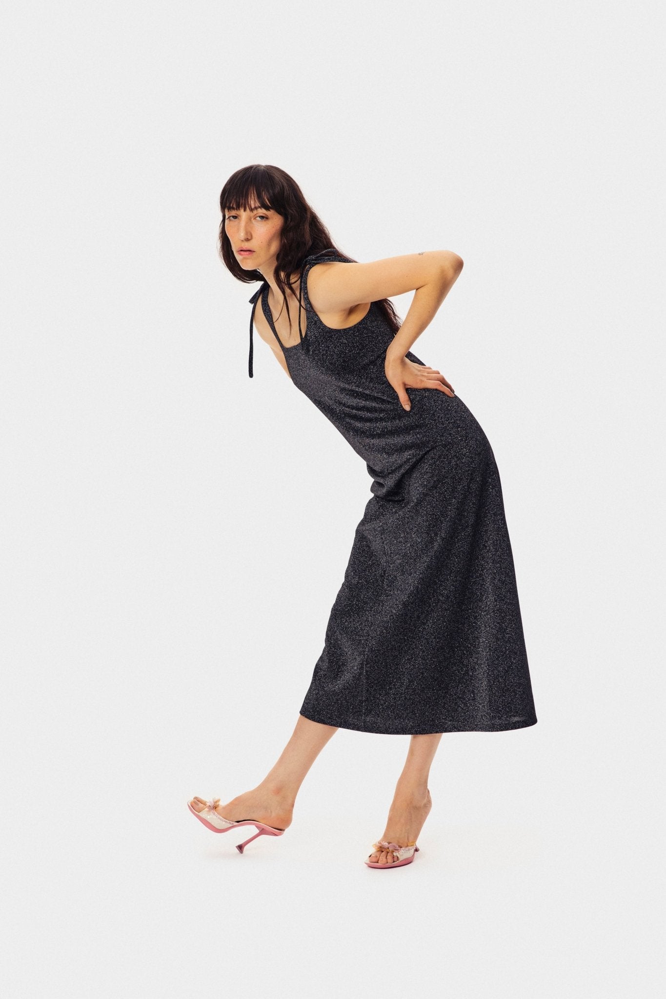 Woman bending in the Kylie Lurex Slip Dress in Black.