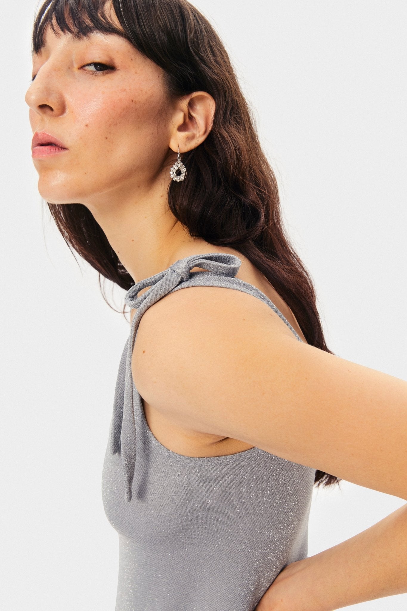 Tied shoulder bows on the Kylie Lurex Slip Dress in Silver worn by a woman.