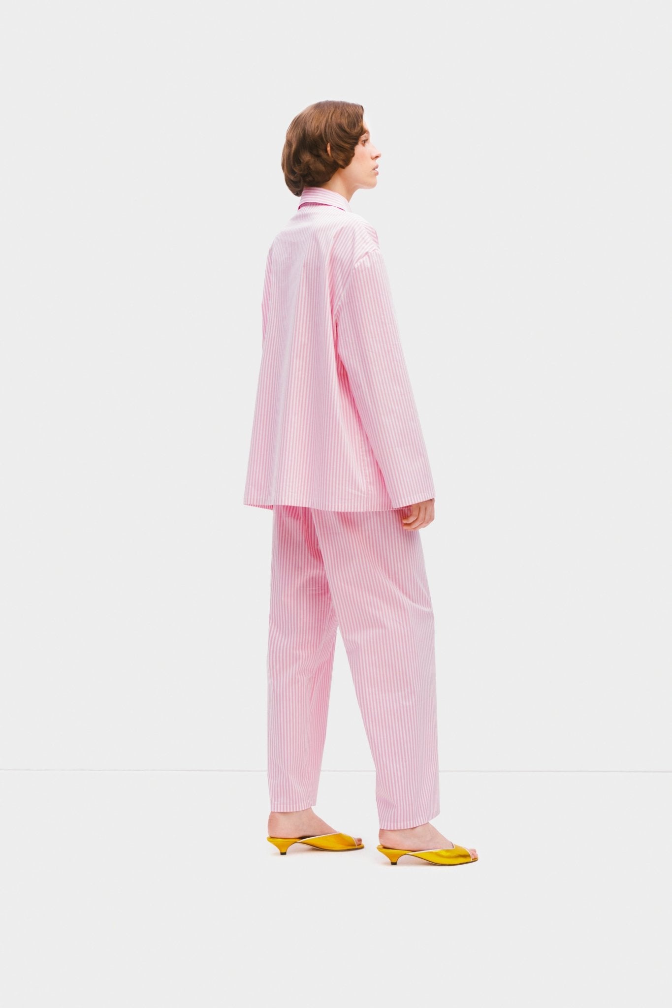 Side of woman wearing pink stripe Lyra Cotton-Poplin Pyjama Set.