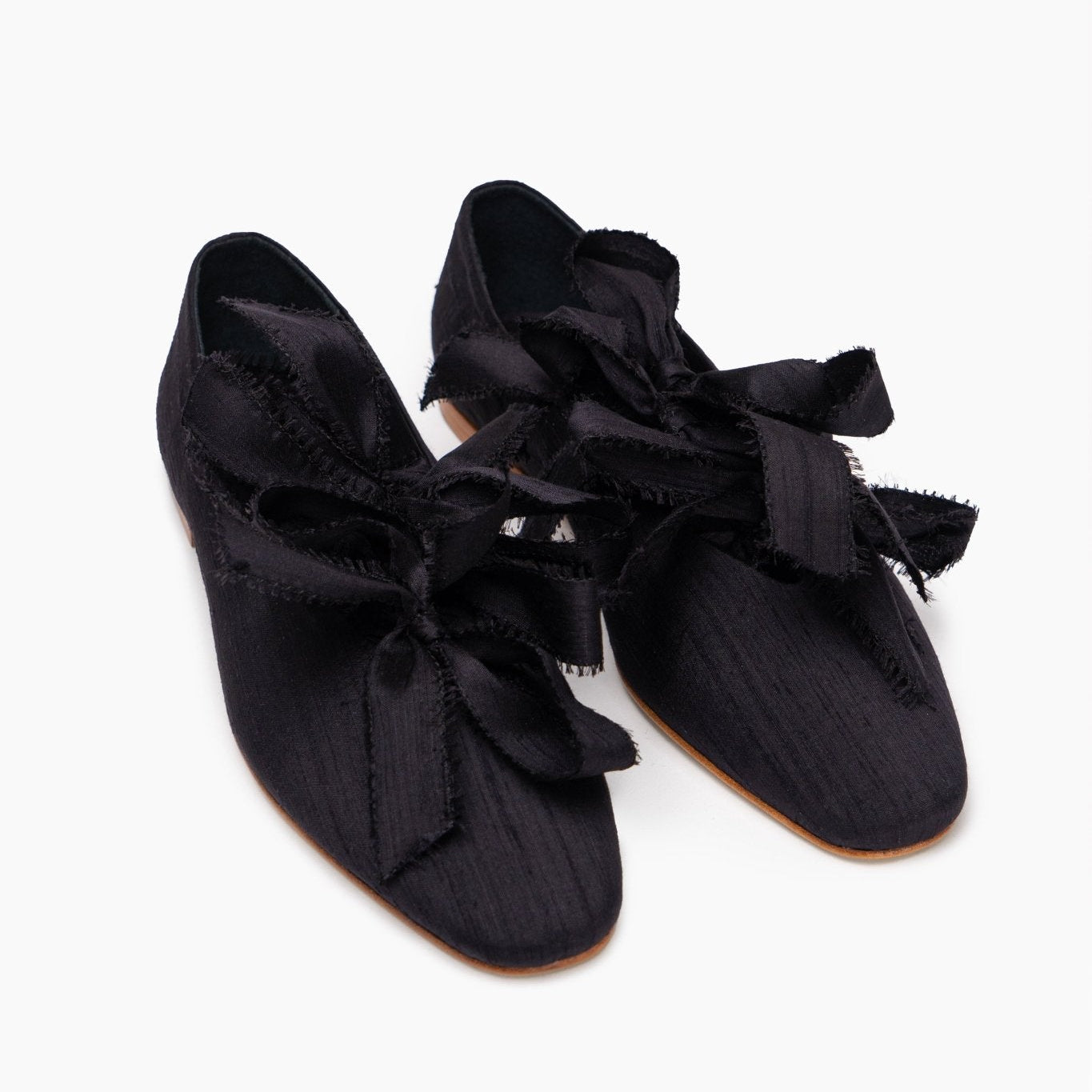 Pair of black silk and leather ballet flats with bows.
