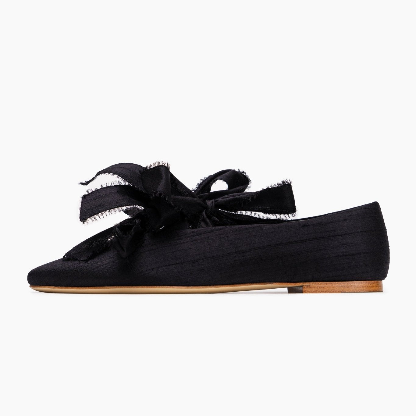 Side view of black silk and leather low heel ballet flat shoe with bows.