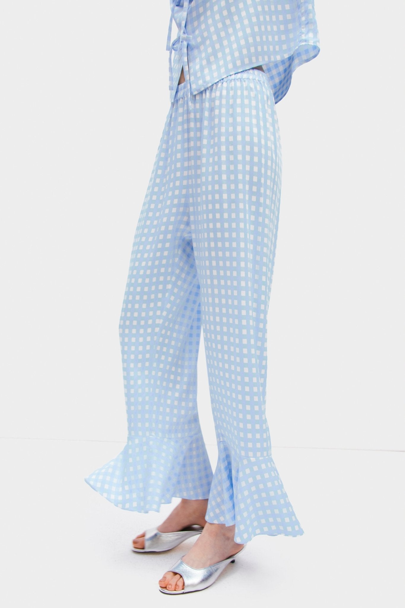 Person wearing blue vichy Pyjama Set showing elastic waist on pants with ruffles at leg openings.
