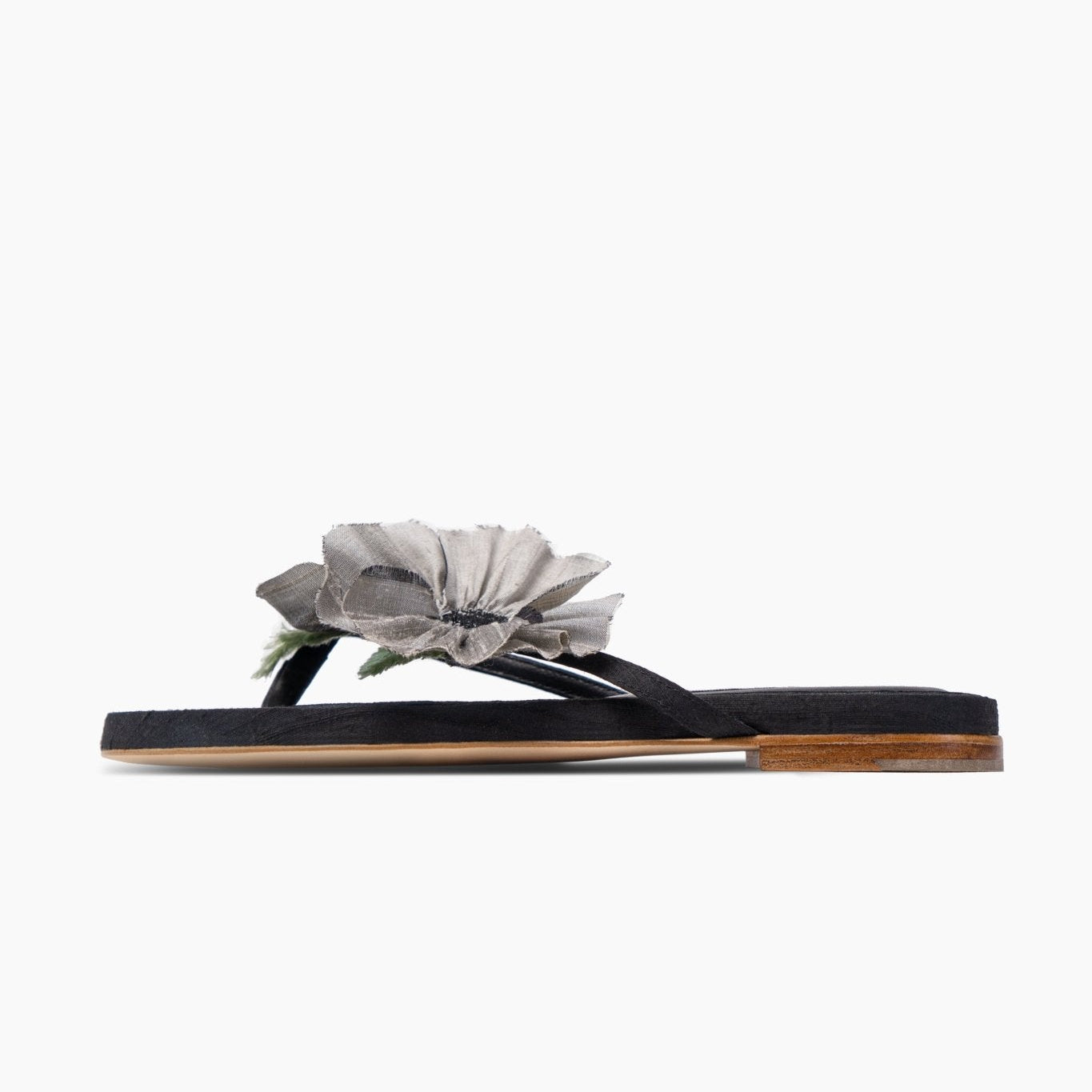 Side of black leather slides with grey silk poppy flower decoration and low heel.
