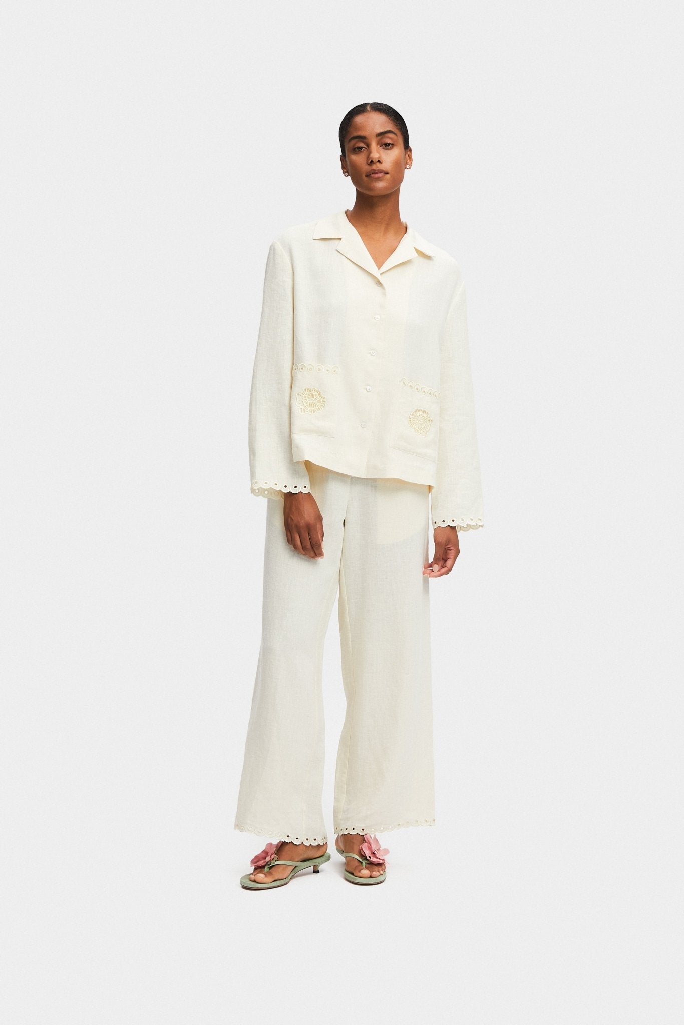Woman wearing a cream shirt and pants with scalloped embroidery on sleeve cuffs and hem - ANNIE.G